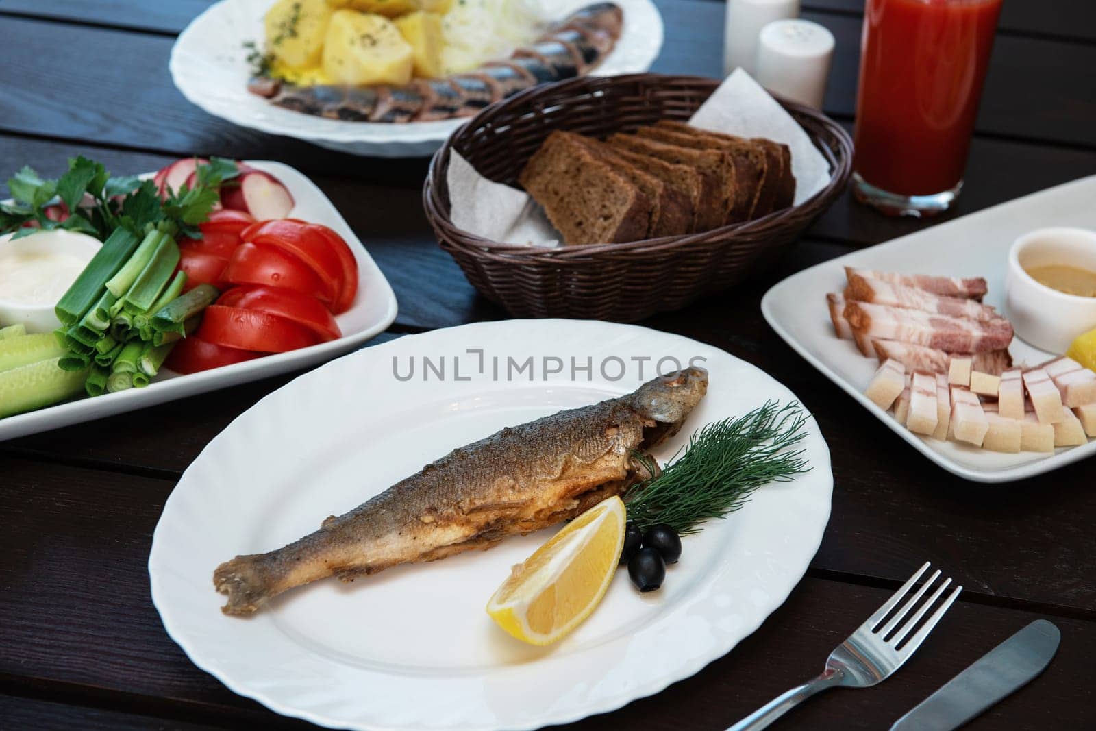 Fried grayling fish on a plate with any appetizers on swimming pool background. Resting and relaxing concept.