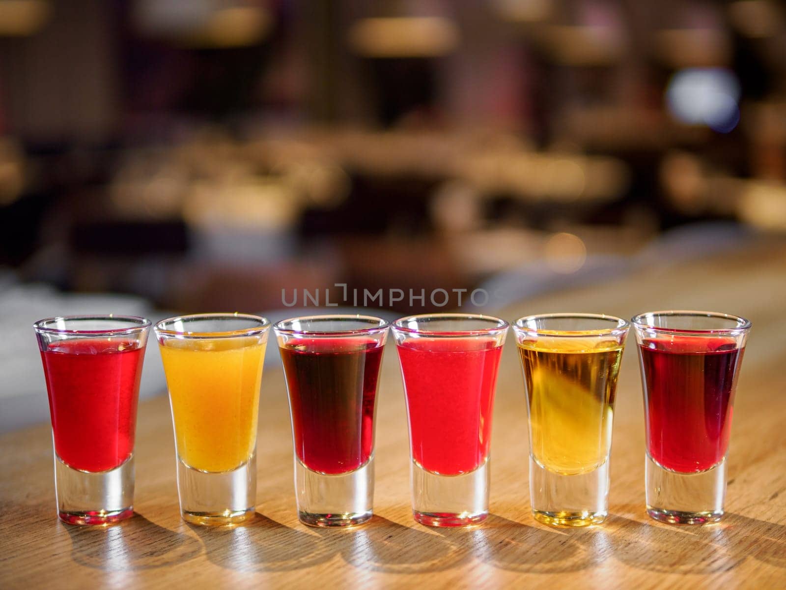 Set of colorful different bitters and liqueurs in shot glasses on bar counter. Collection of shooters. Selection of natural berry alcoholic tinctures in glasses. Different bitters and liqueurs