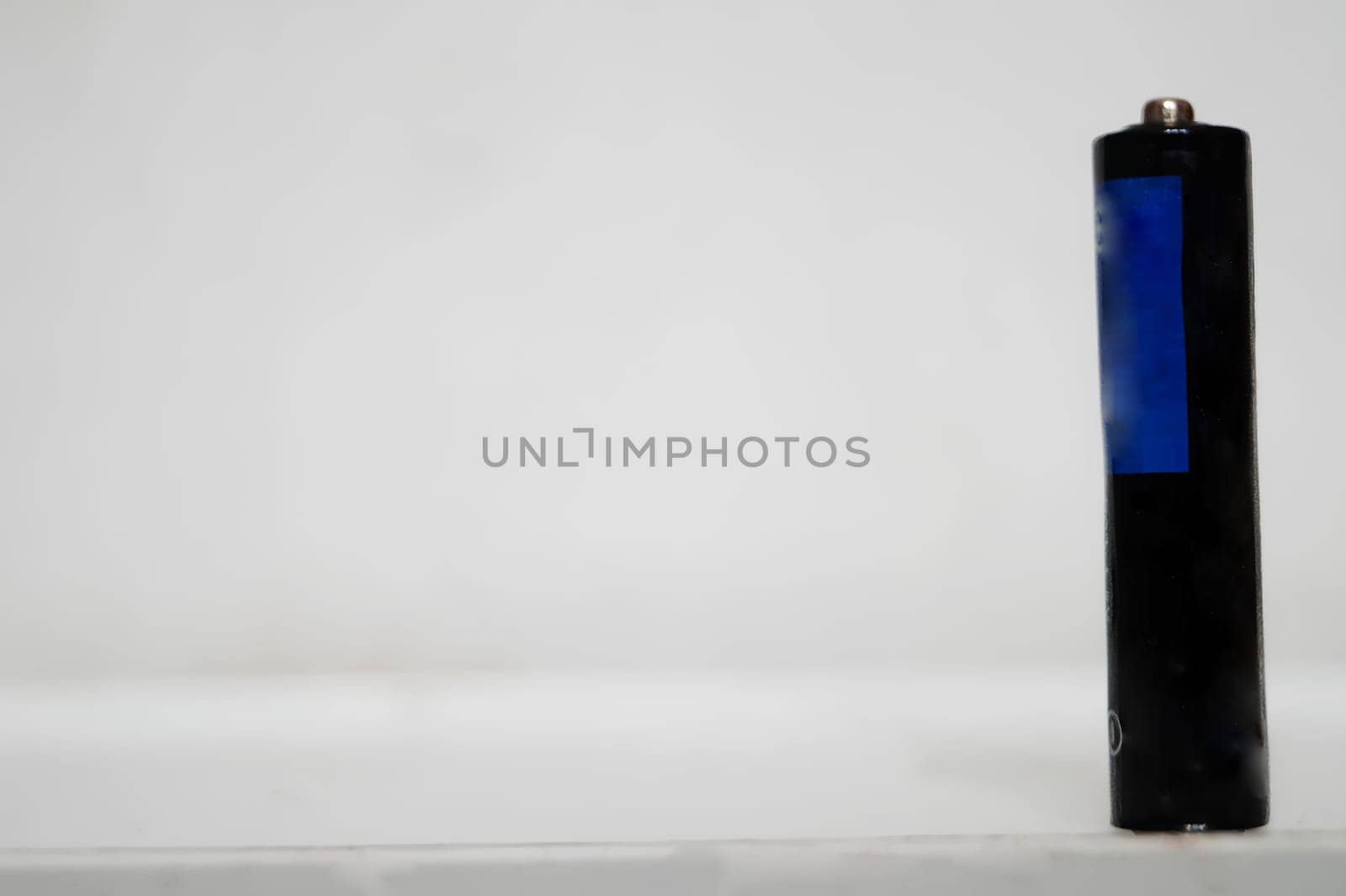 Single AAA-Size Battery Standing Upright on a White Surface