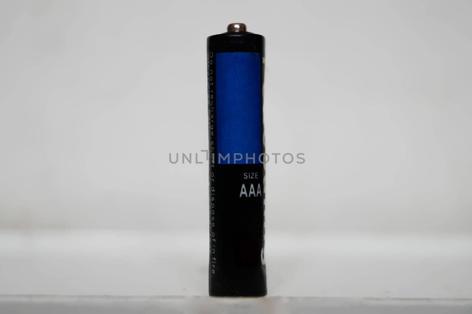 Single AAA-Size Battery Standing Upright on a White Surface