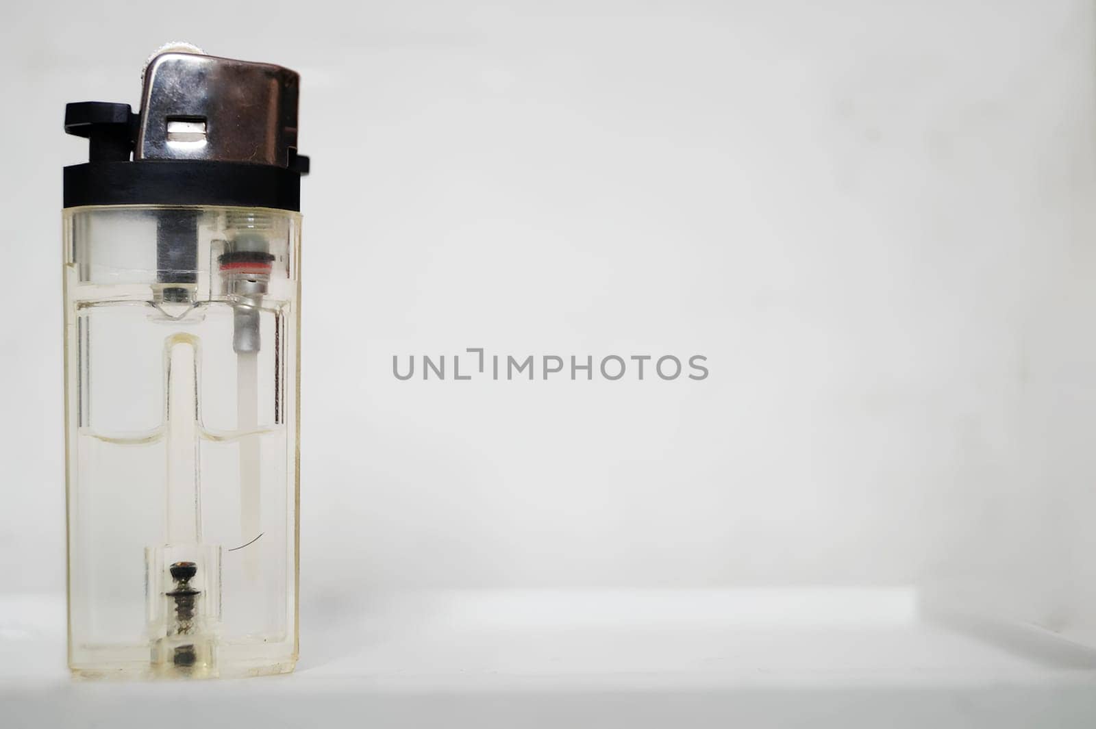 Transparent Plastic Lighter With Brown Cap Against a White Background