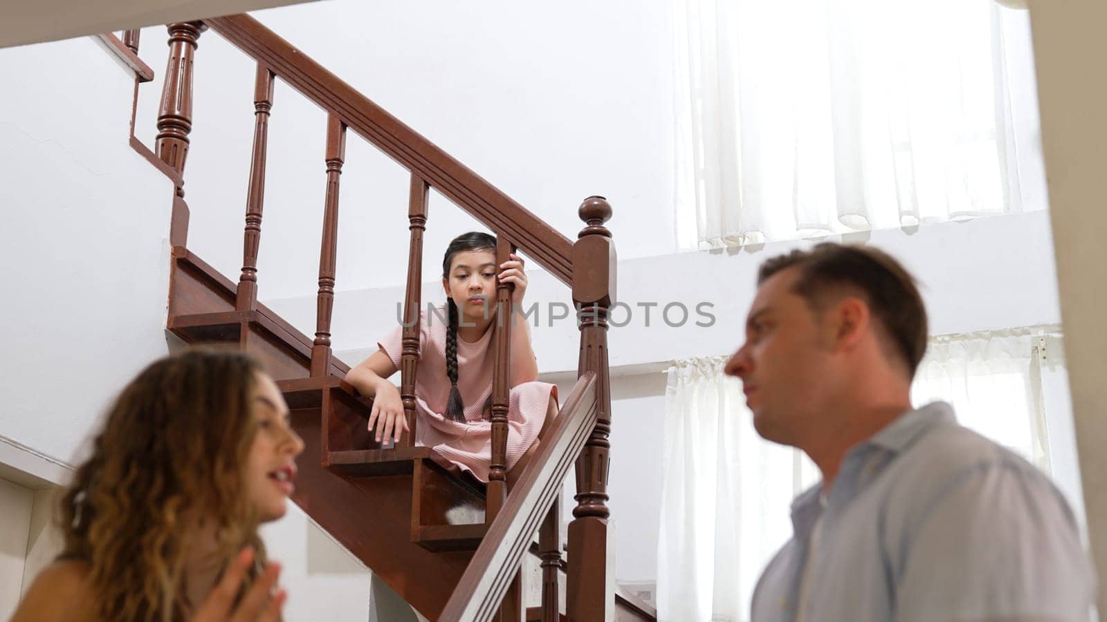 Stressed and unhappy young girl watch her parent arguing from the stair. Domestic violence at home and traumatic childhood develop to depression and anxiety. Unhealthy family concept. Synchronos