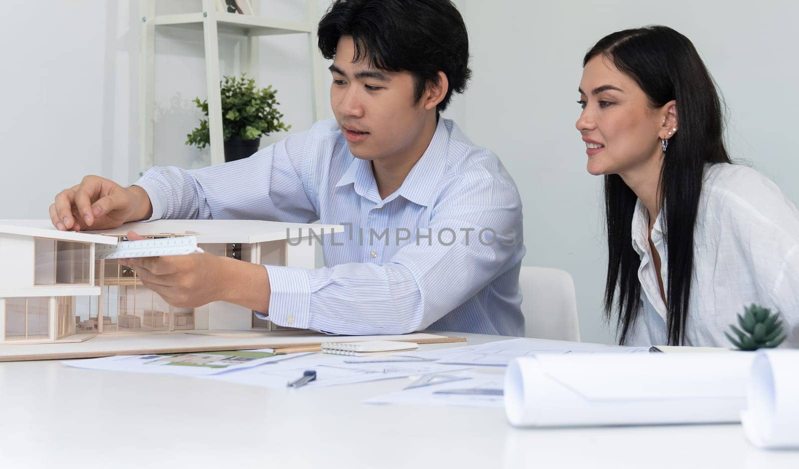 Portrait of cooperative engineer team working together to measure house model by using ruler and architectural equipment. Creative business design and teamwork concept. Immaculate..