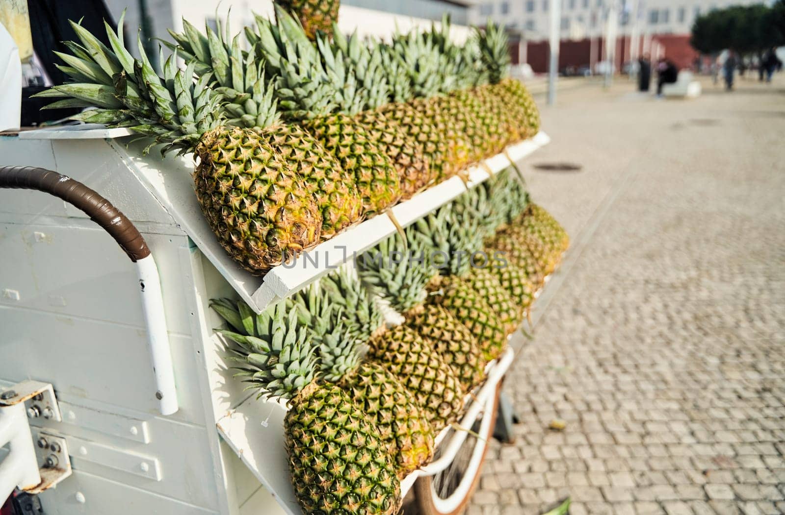 A cart filled with pineapples on a cobblestone street by driver-s