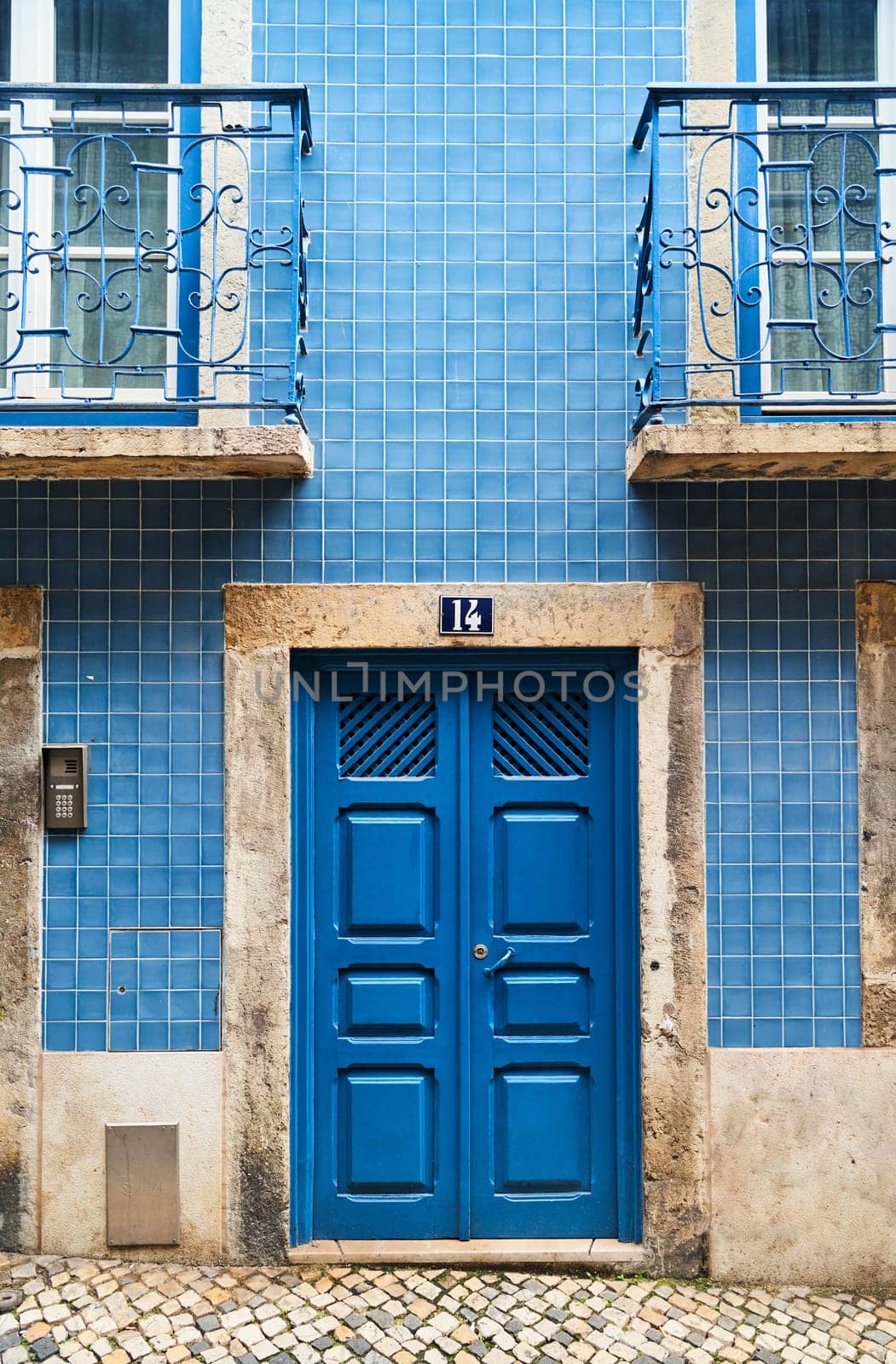 A blue rectangle wood door with the number 13 on a brick facade by driver-s