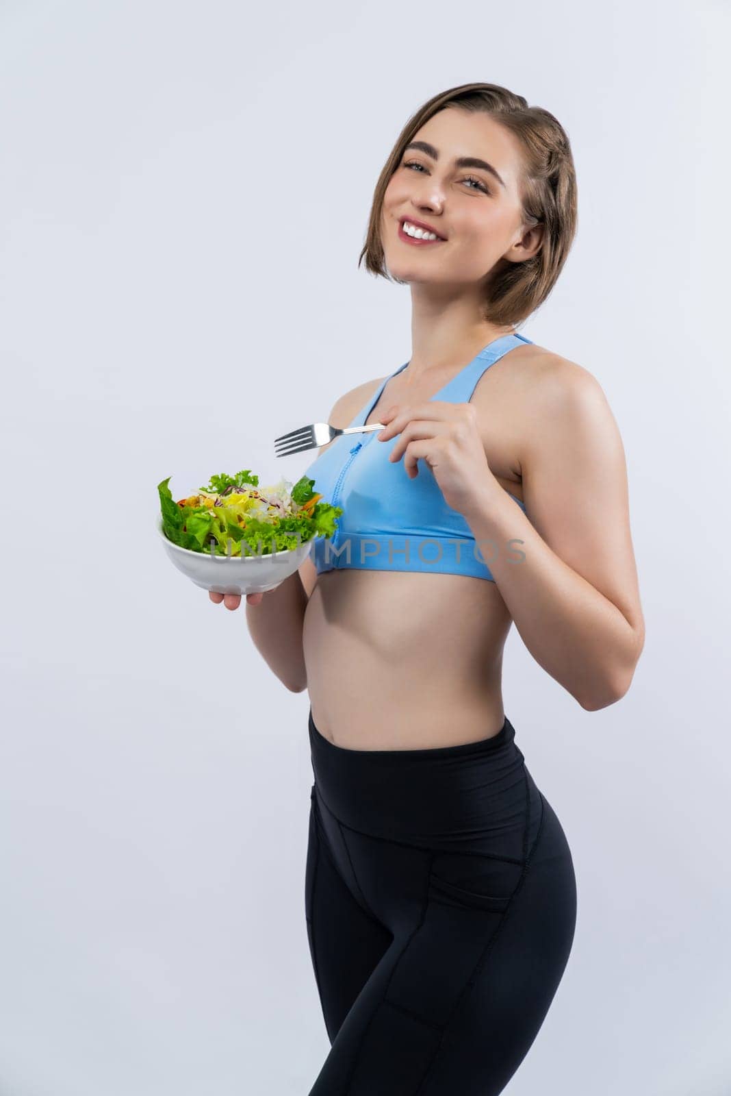 Full body length gaiety shot athletic and sporty young woman with healthy vegan food in standing posture on isolated background. Healthy active and body care by vegetarian lifestyle.