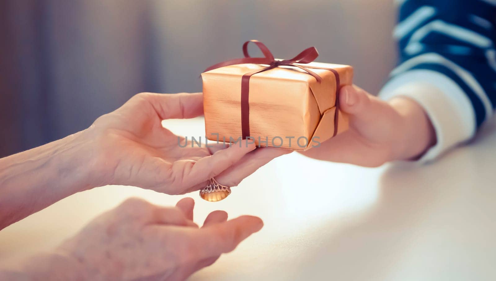 Female hands hold a gift closeup, top view. A young girl gives a nice packed surprise to her mother, grandmother with love, remembers elderly relatives, visits during holidays, takes care of them.