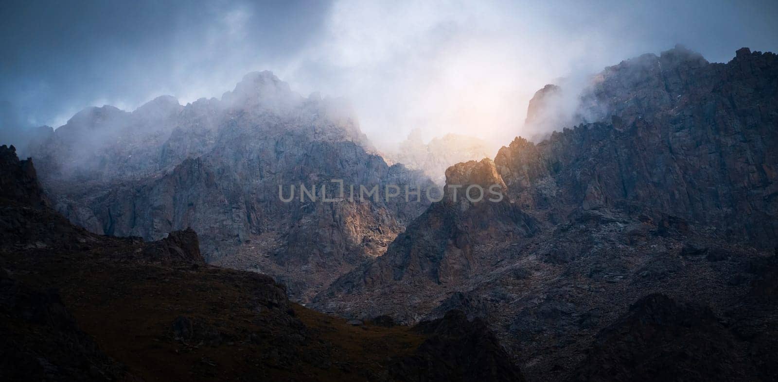 Thunder warning in the mountains, picturesque majestic rocky mountains scenery with an impending storm and the last light of the sun at sunset, wild nature without people.