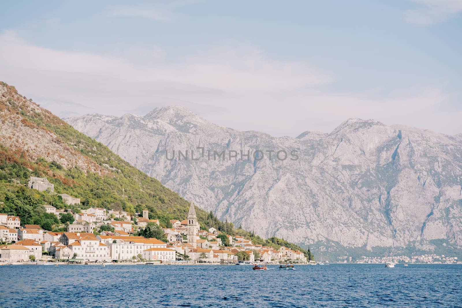 Ancient houses of Perast on the shore of the Bay of Kotor with an ancient bell tower against the backdrop of the mountains. Montenegro by Nadtochiy