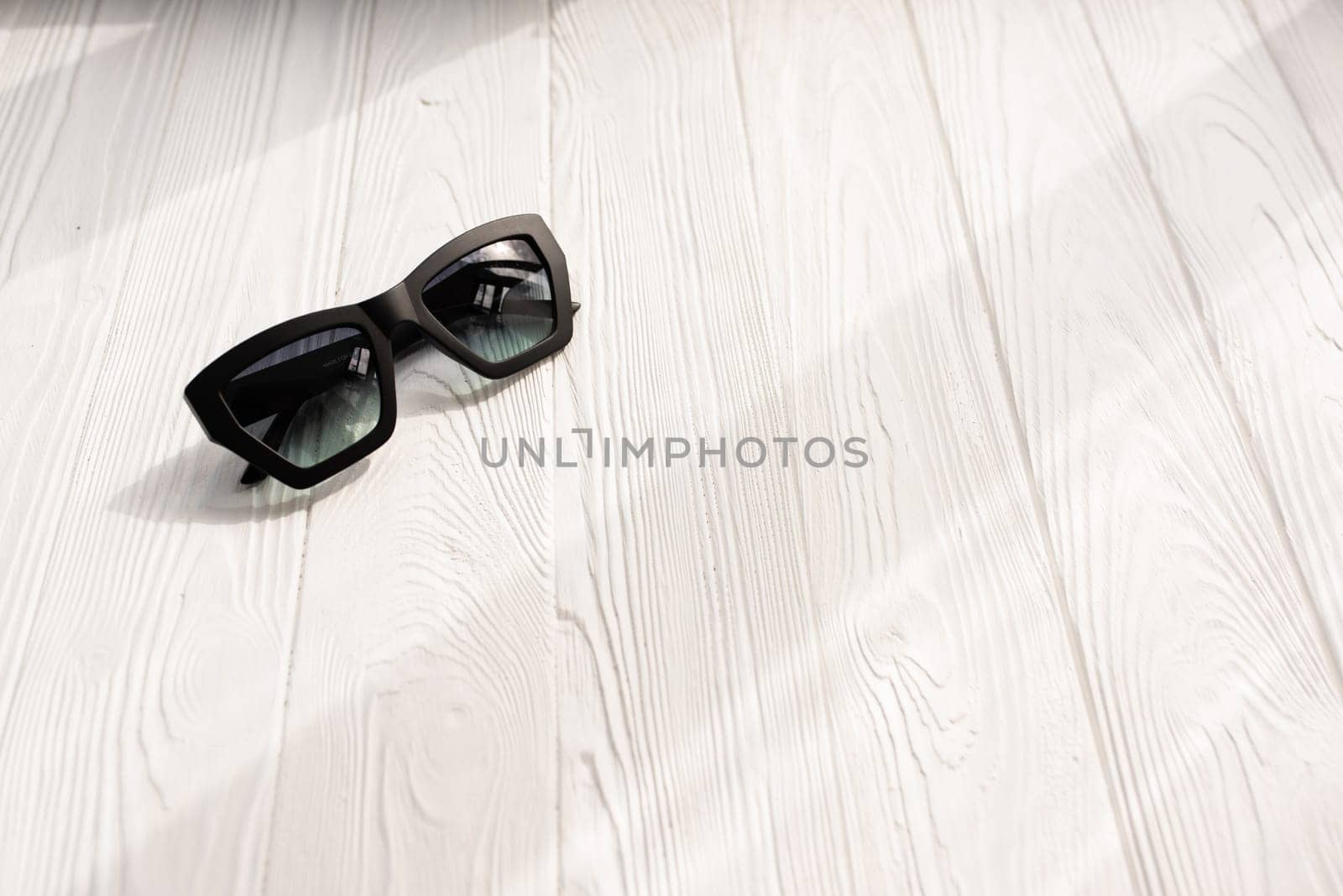 Stylish black sunglasses. Summer background mockup template text. pattern top view above white wooden background. Summer fashion accessories for beach. Women design sunglasses. Vacation concept