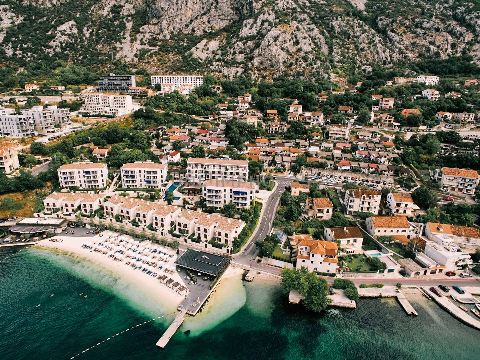 Aerial view of Huma Kotor Bay Hotel and Villas on the seashore at the foot of the mountains. Dobrota, Montenegro. High quality photo