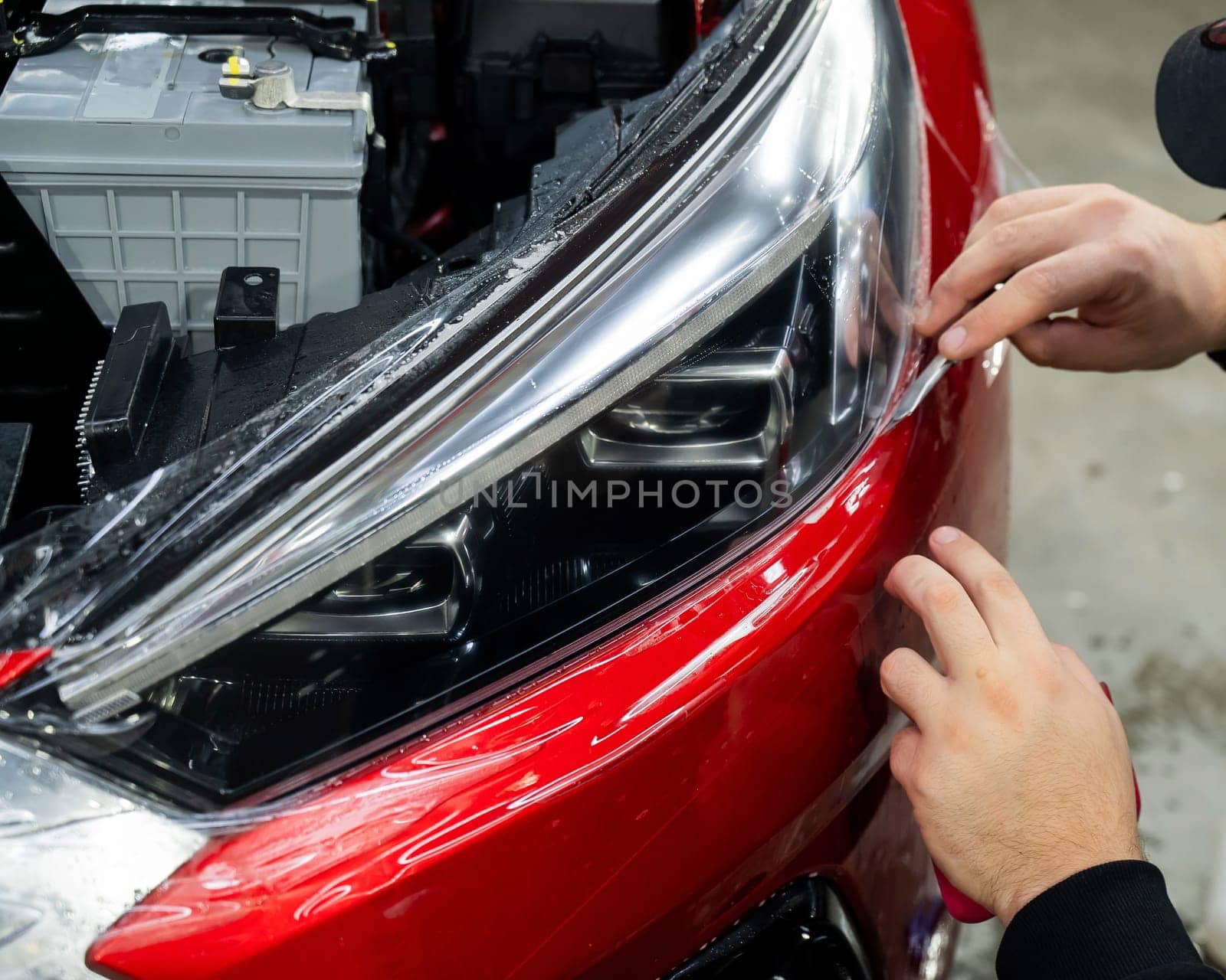 The process of applying protective vinyl film to car headlights in detailing