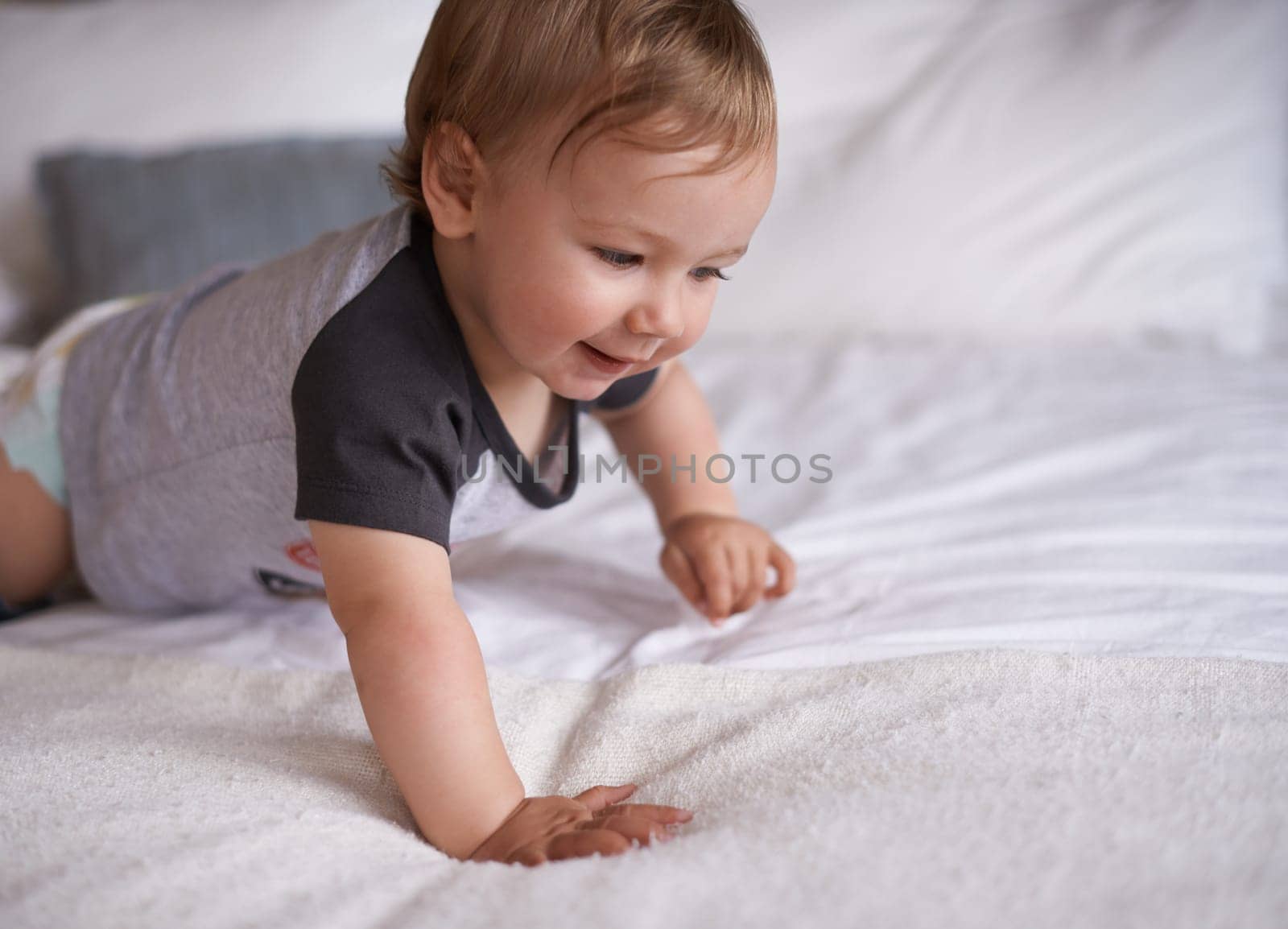 Boy, baby and learning to crawl in home, bed and kid for motor skills in bedroom on weekend. Child development, happy toddler and calm or comfortable, wellness and curious for health and growth.