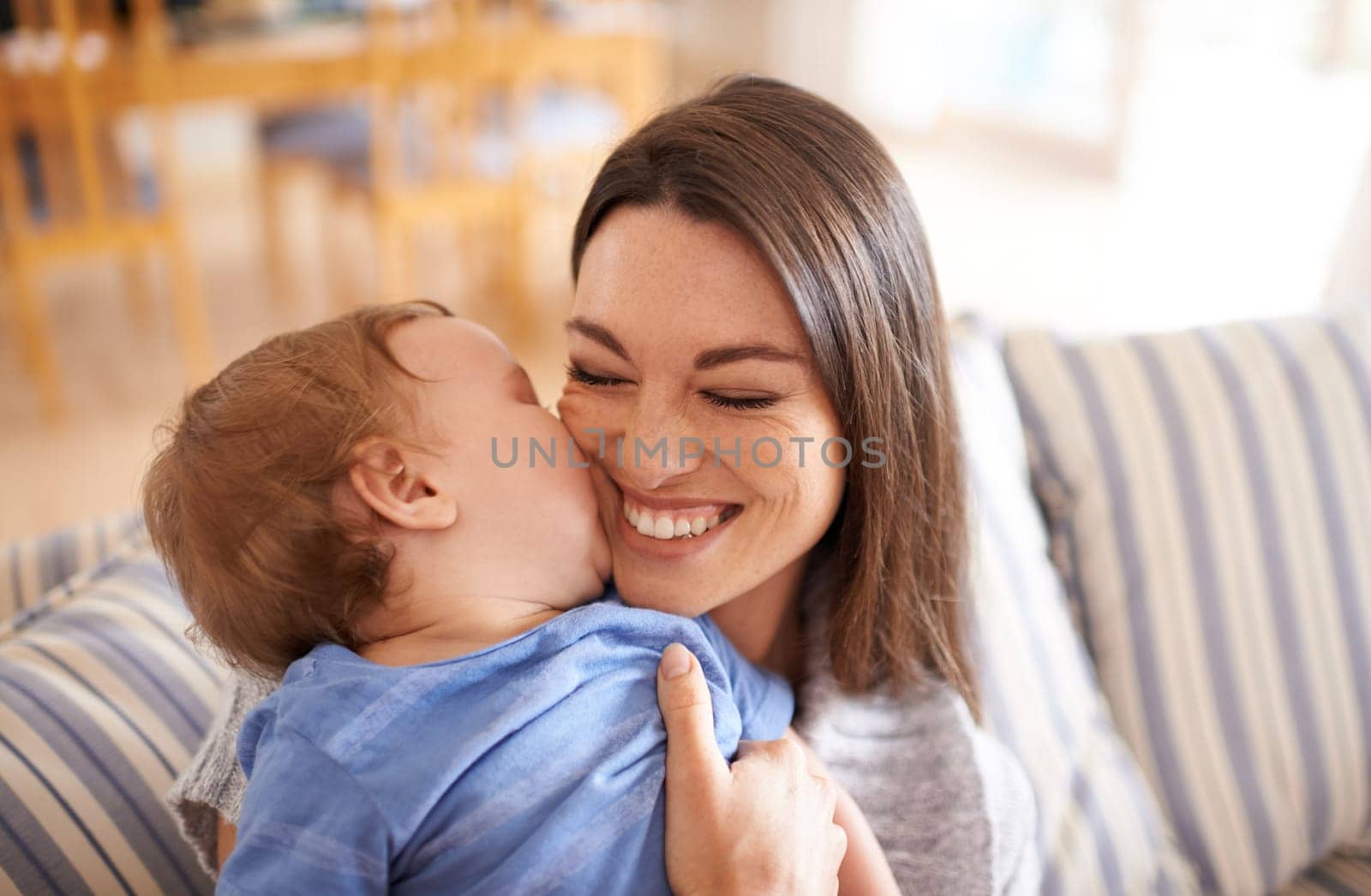 Mother, baby and kiss for love in embrace, care and support or relax in living room and comfortable. Mommy, son and affection for bonding in childhood, security and happiness in hug or smile on face.