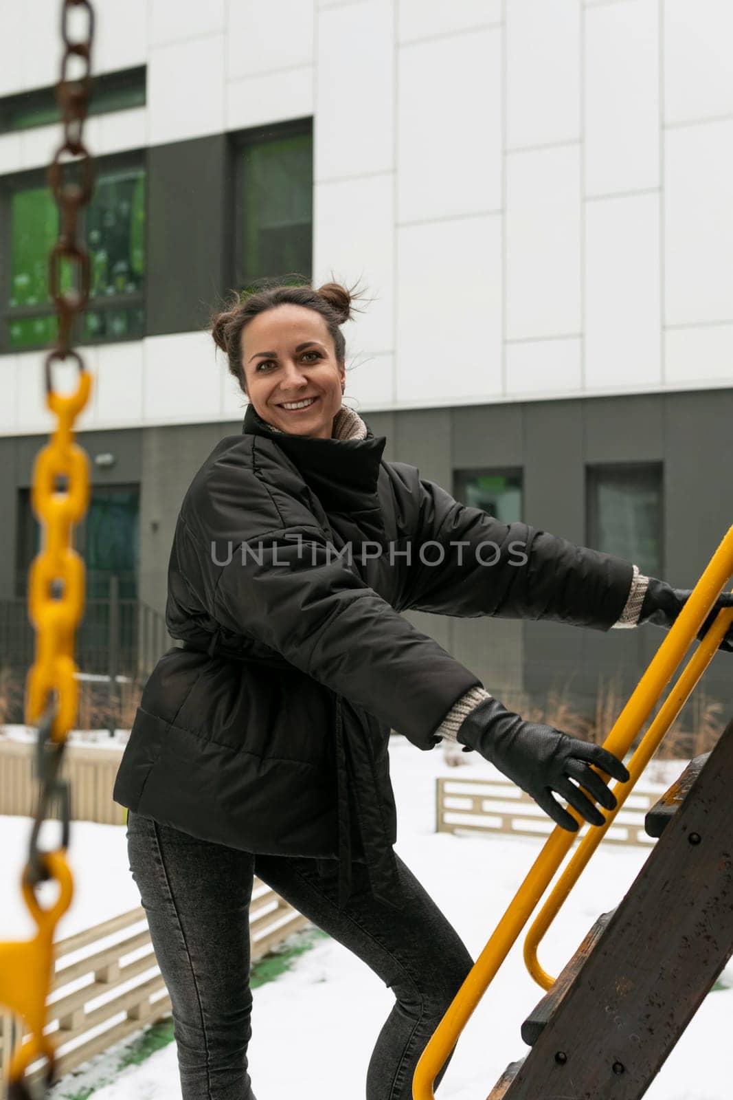 Young pretty woman in a winter jacket fooling around on the playground by TRMK