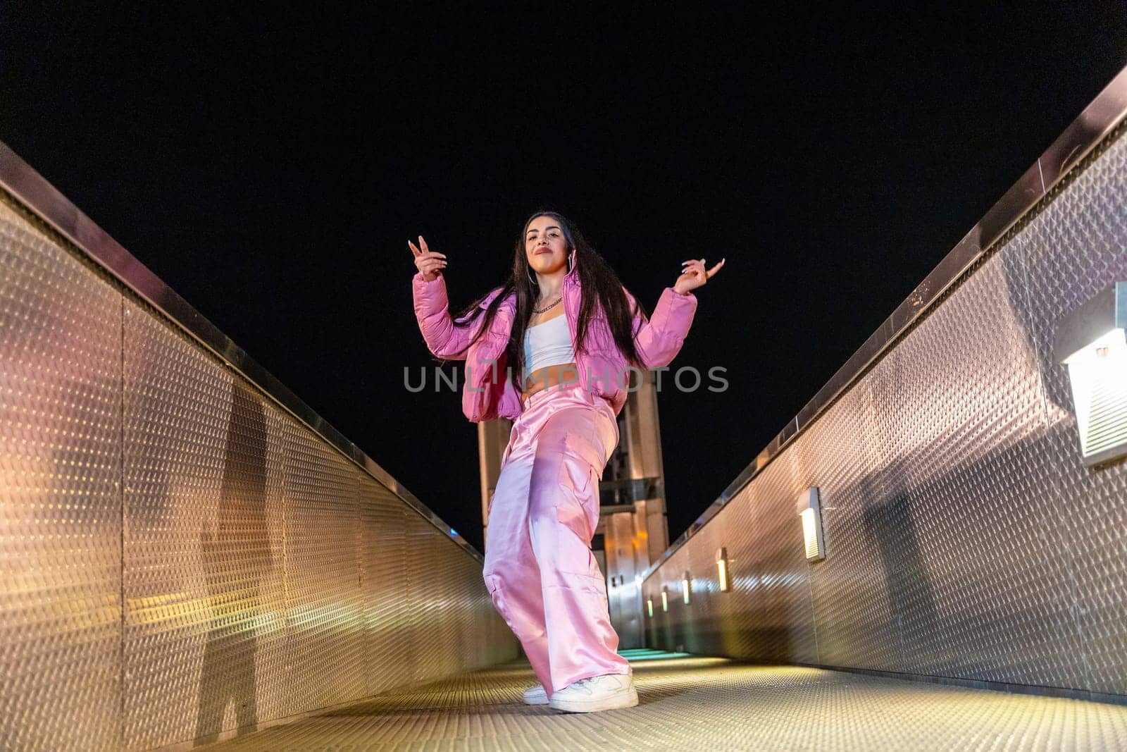 Low angle view photo of a happy trap dancer in pink clothes dancing alone outdoors at night