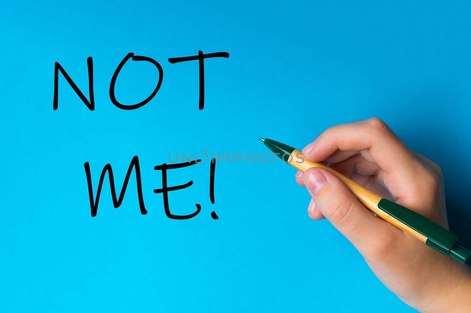 Children hand with pen write on a blue white background. Writing hand. Word Not me