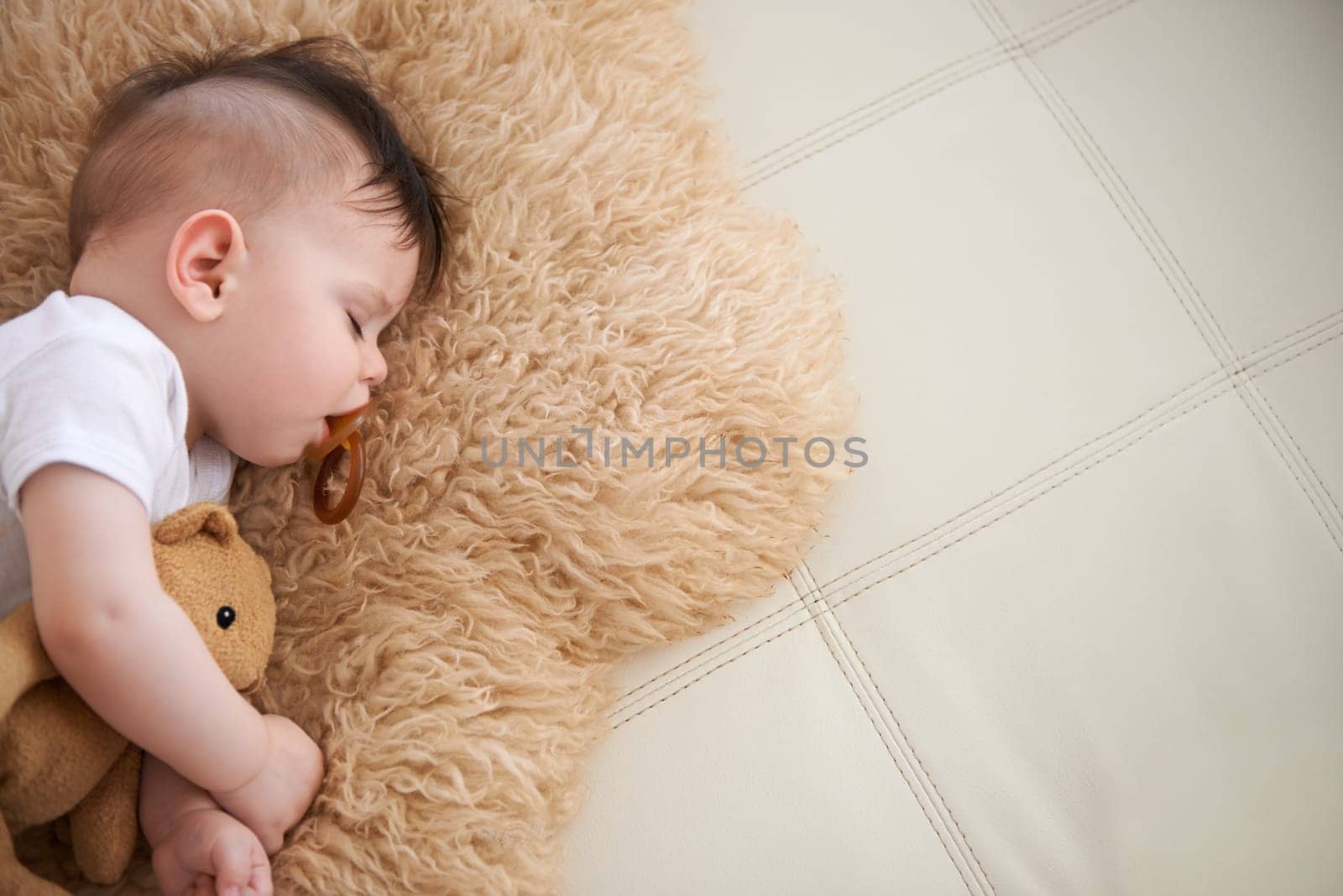 Baby, sleep and cuddle with teddybear on couch at home, rest and relax with dummy and dream. High angle, toddler, and nap in sofa for child development, growth and innocent with peace for bedtime. by YuriArcurs