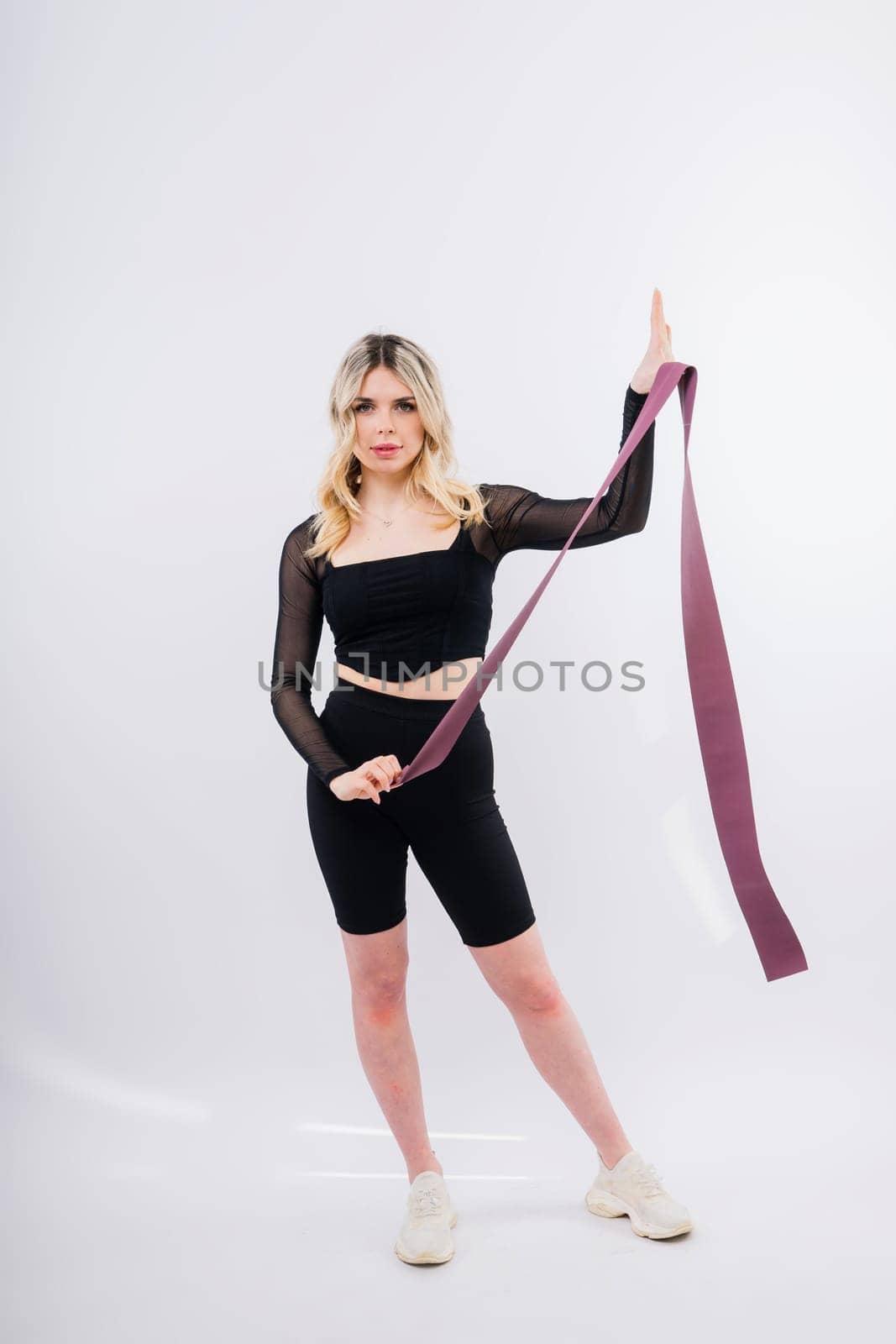Young woman workout with resistance band on white background. Strength and motivation. by Zelenin