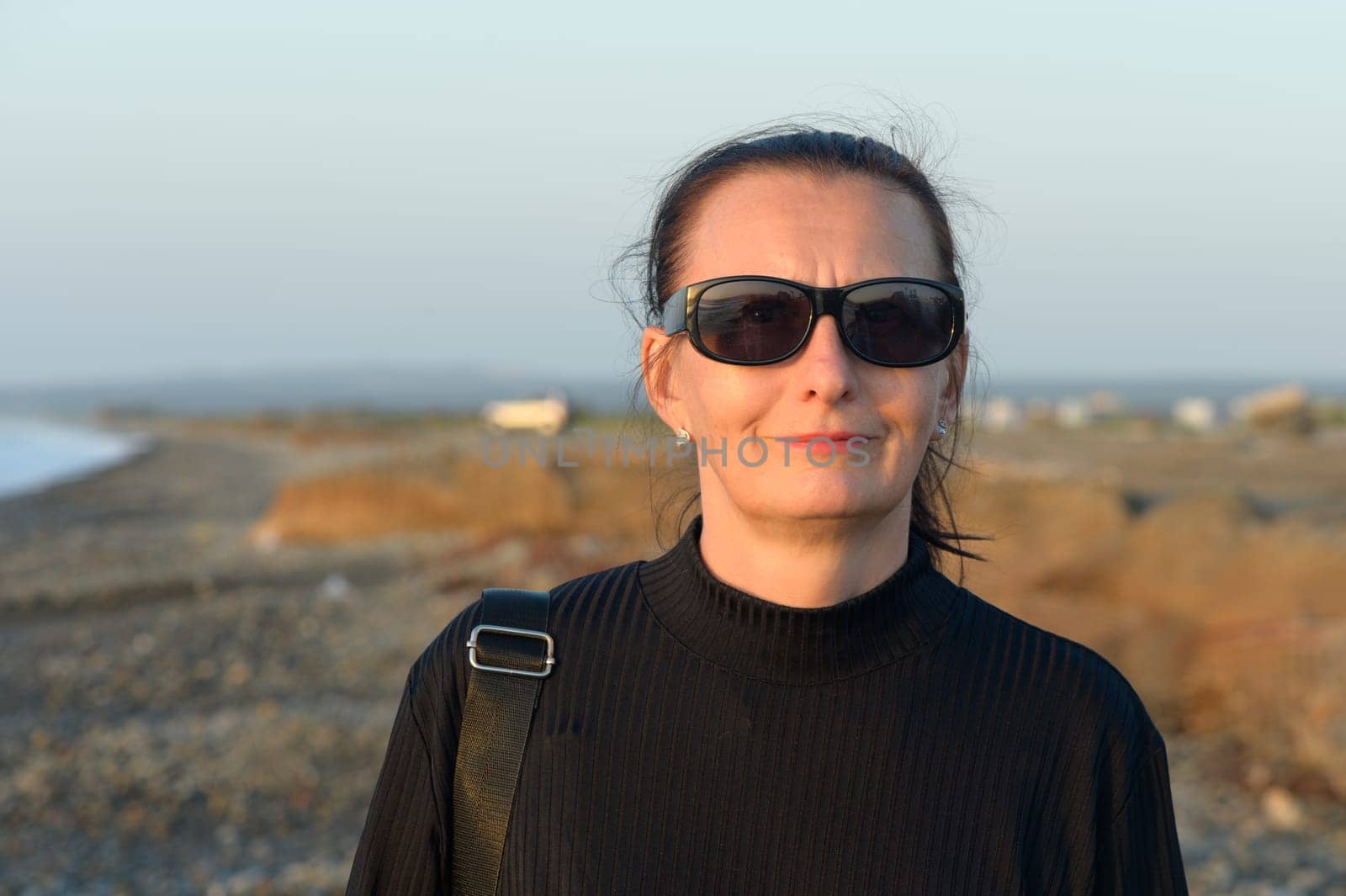 woman in sunglasses walking on the beach mediterranean sea
