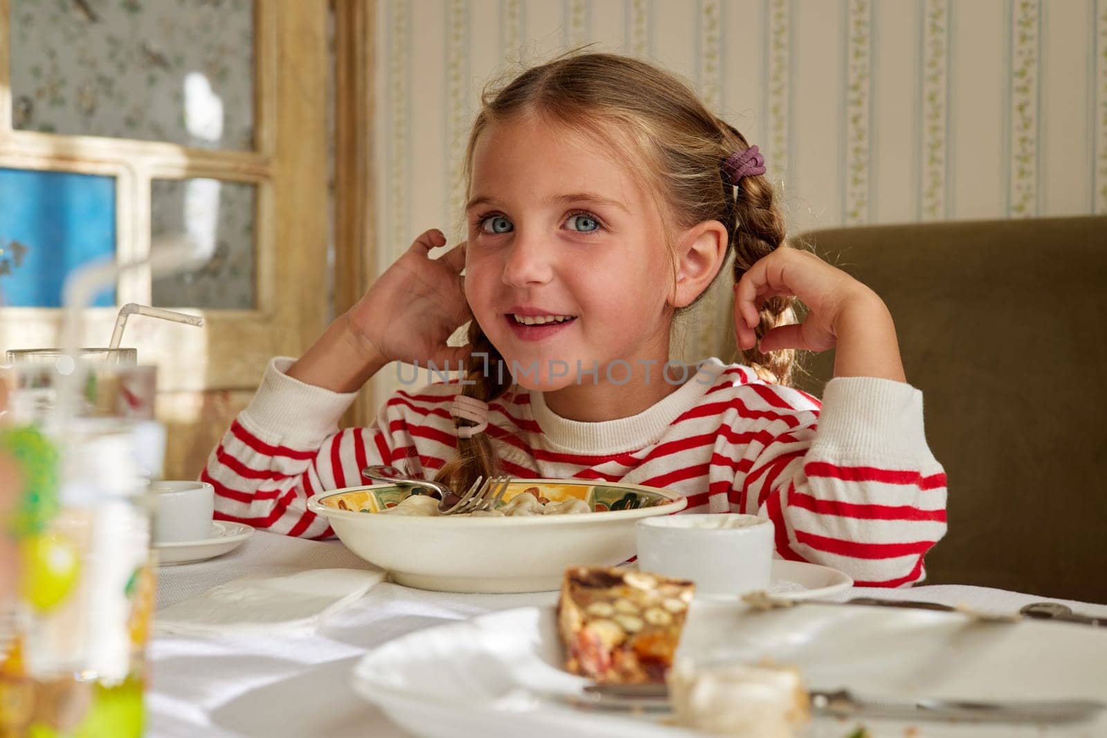 Cute smiling little girl sitting at the dinner table by Demkat