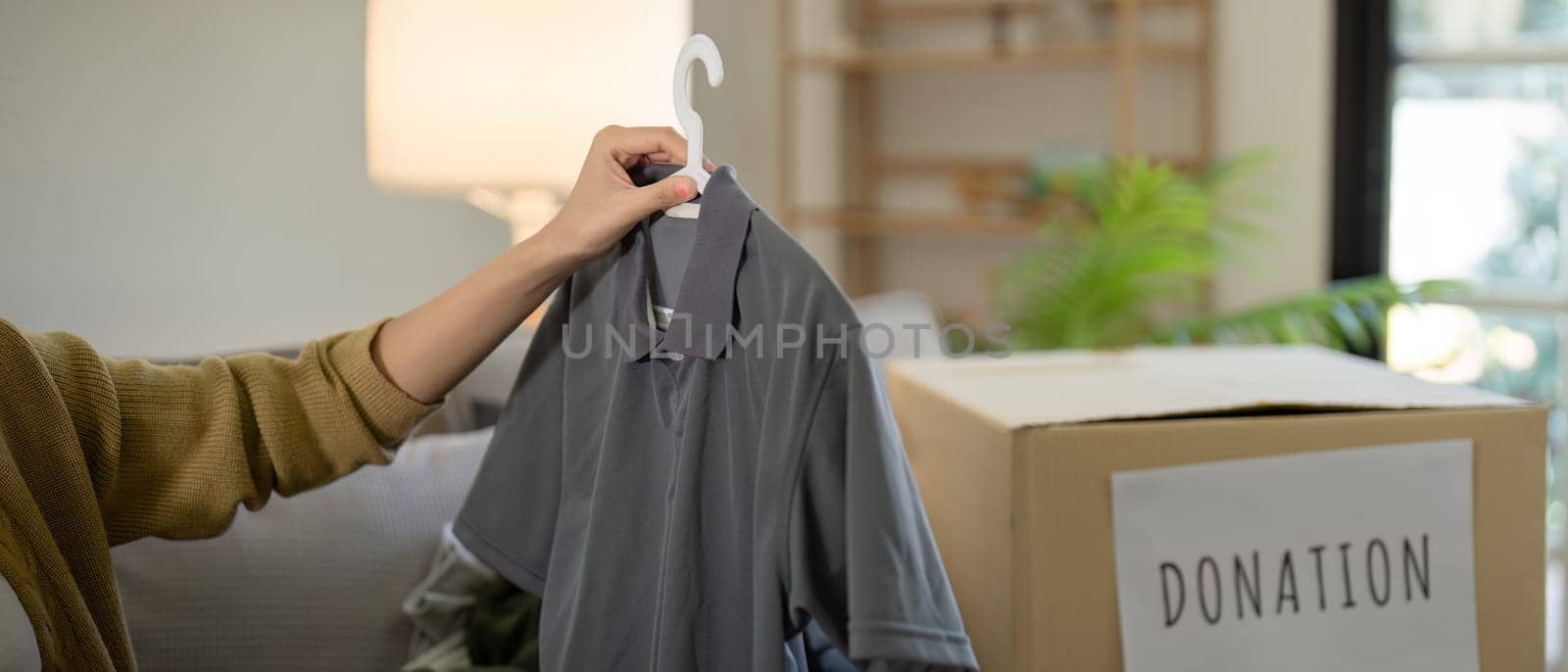 Donation, asian young woman sitting pack object at home, putting on stuff into donate box with second hand clothes, charity helping and needy people. Reuse recycle by nateemee