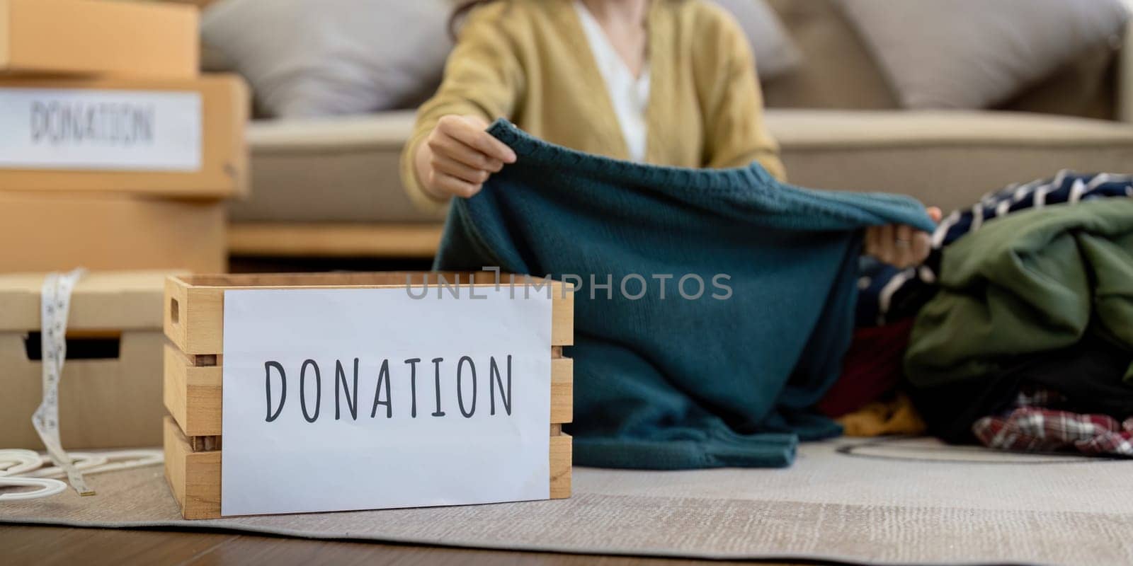 Donation, asian young woman sitting pack object at home, putting on stuff into donate box with second hand clothes, charity helping and needy people. Reuse recycle.