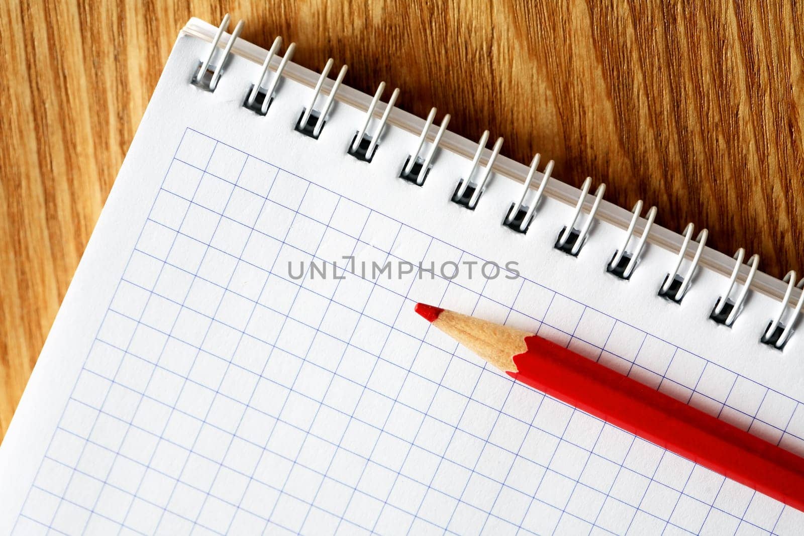 Red pencil on open spiral notebook with blank page