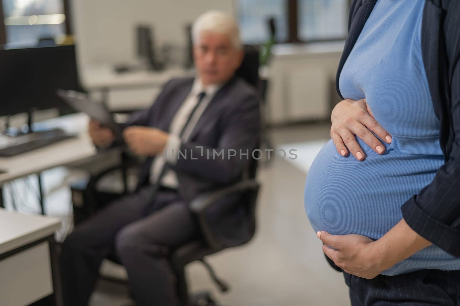 Close-up of belly of pregnant woman working in office