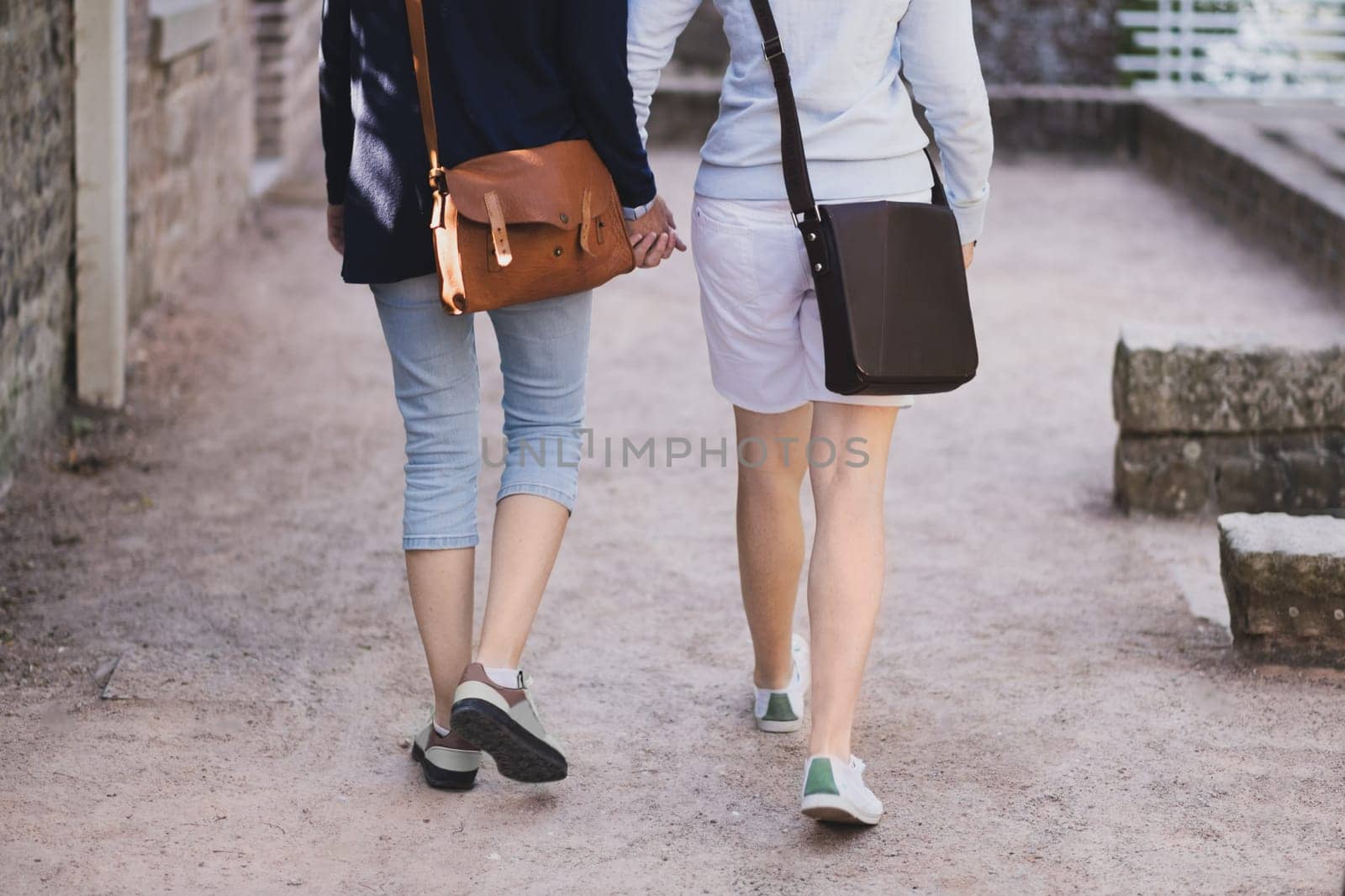 LGBT Two lesbian girls walk around the city and hold hands by Godi