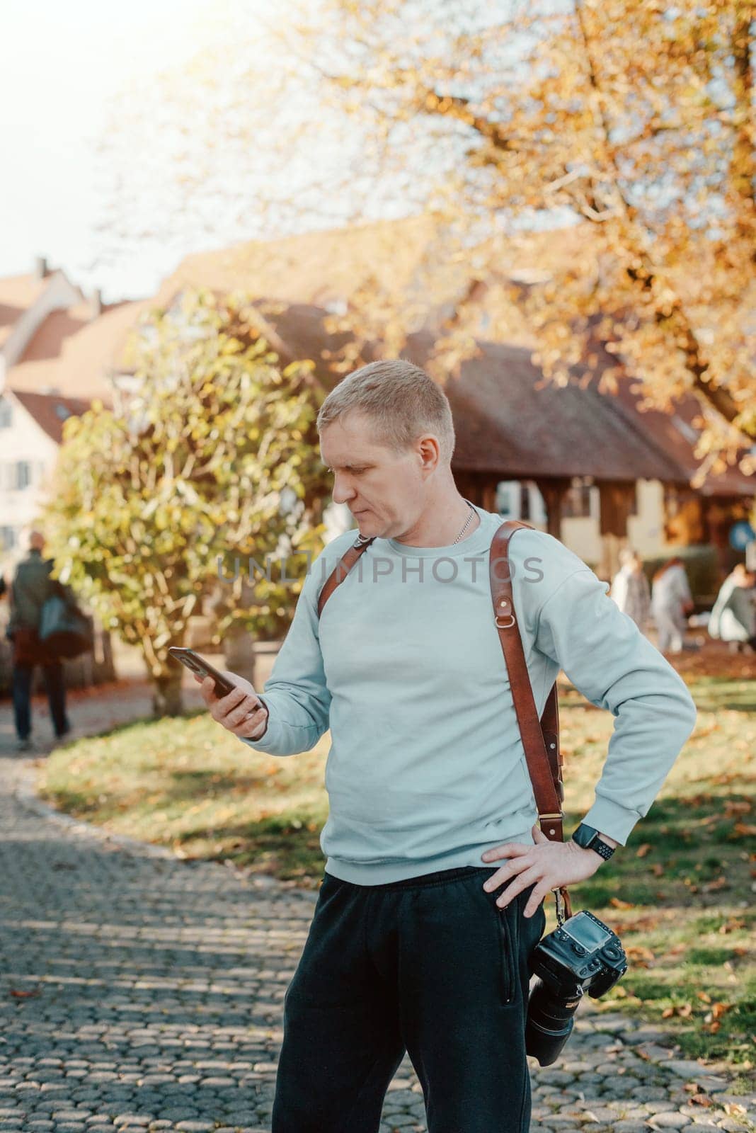 Professional Photographer Taking Picture Of Beautiful Autumn Park. Man Professional Photographer standing With Camera And With Smartphone In Autumn Park. Retouched, Vibrant Colors by Andrii_Ko