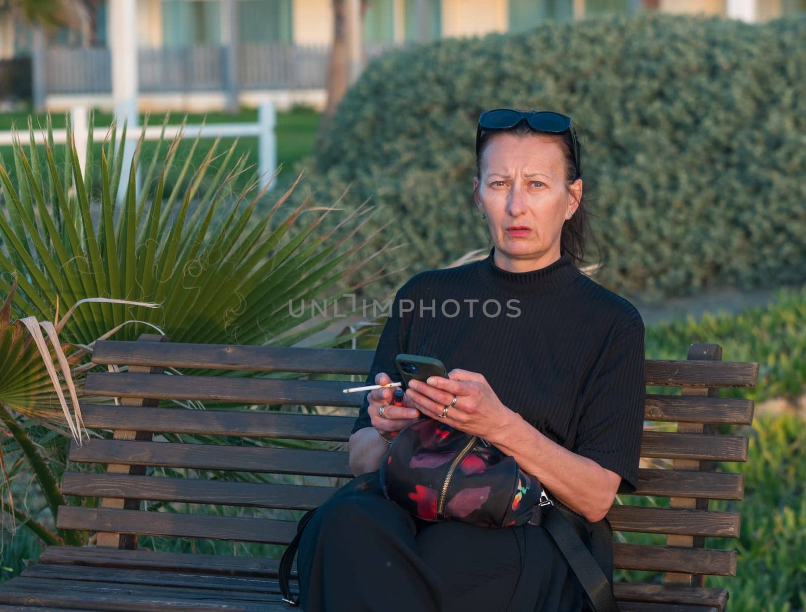 a woman with a cigarette and a phone sits on a bench near the Mediterranean Sea 4 by Mixa74