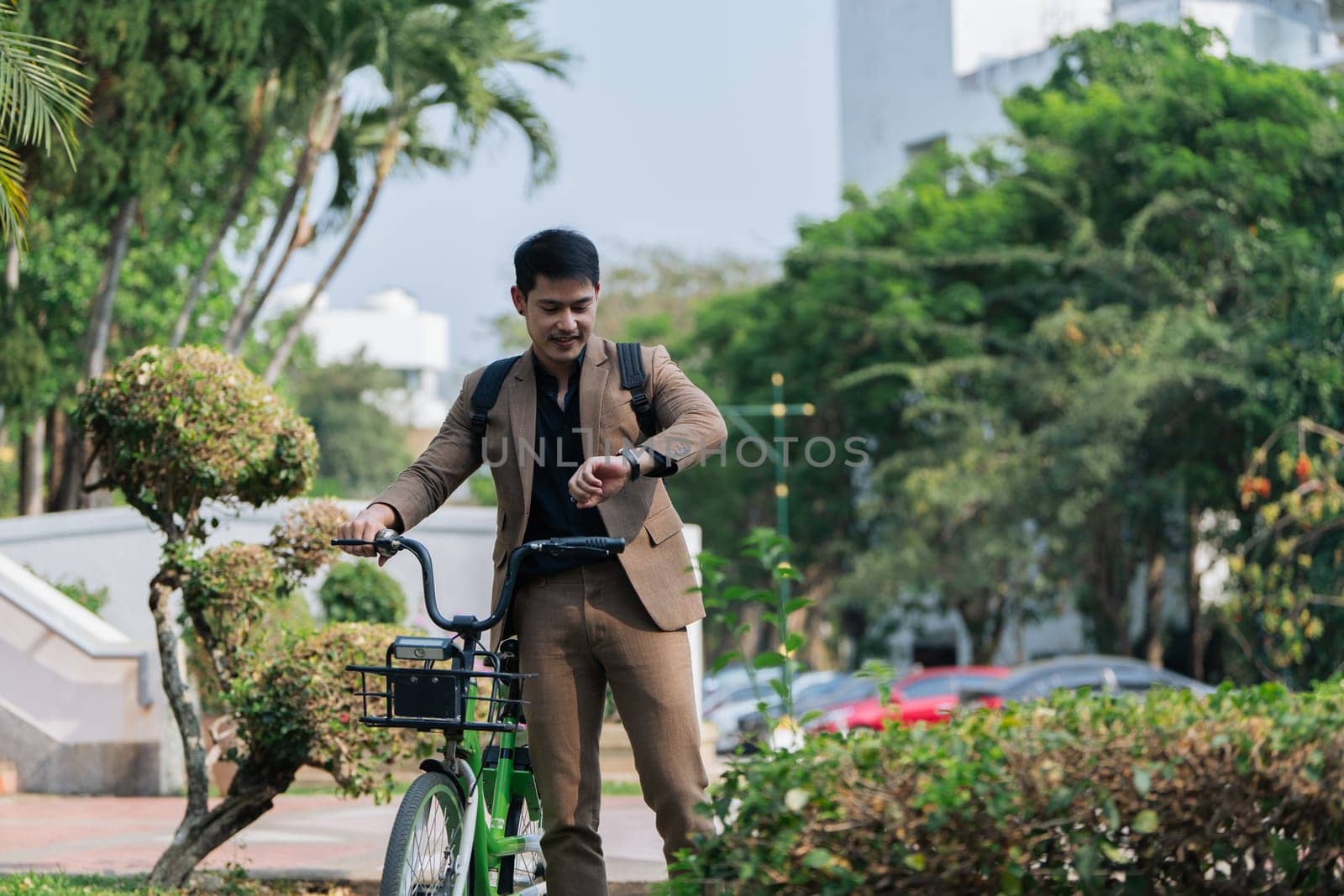 Young businessman in suit in city park bike to work eco friendly alternative vehicle green energy by itchaznong