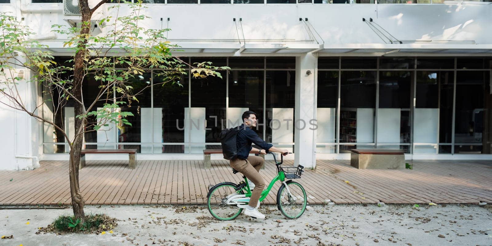 Elegant entrepreneur in smart casual cycling on bicycle track in warm sunny day area of city by itchaznong