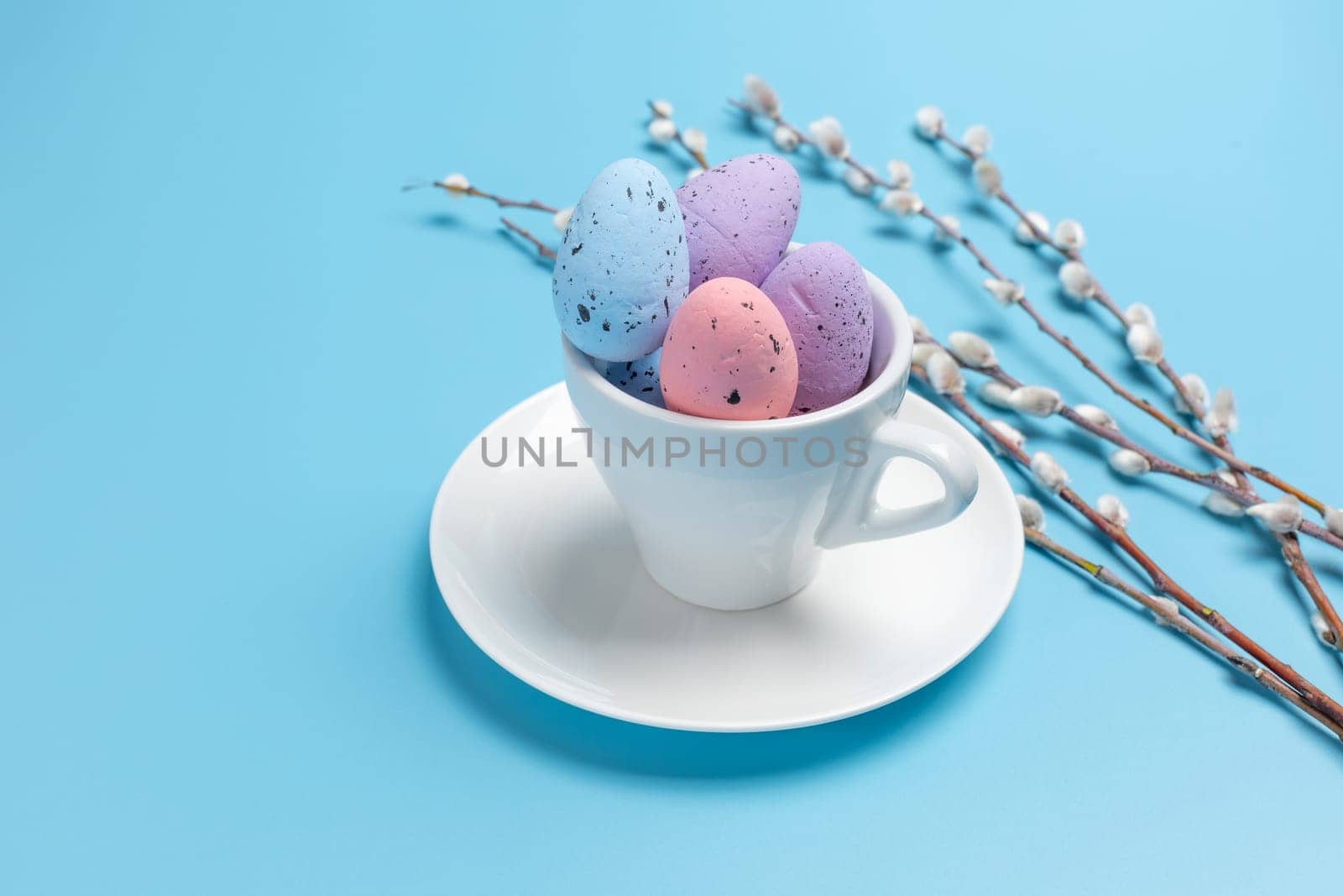 Cup with colored Easter eggs on the blue background. by mvg6894
