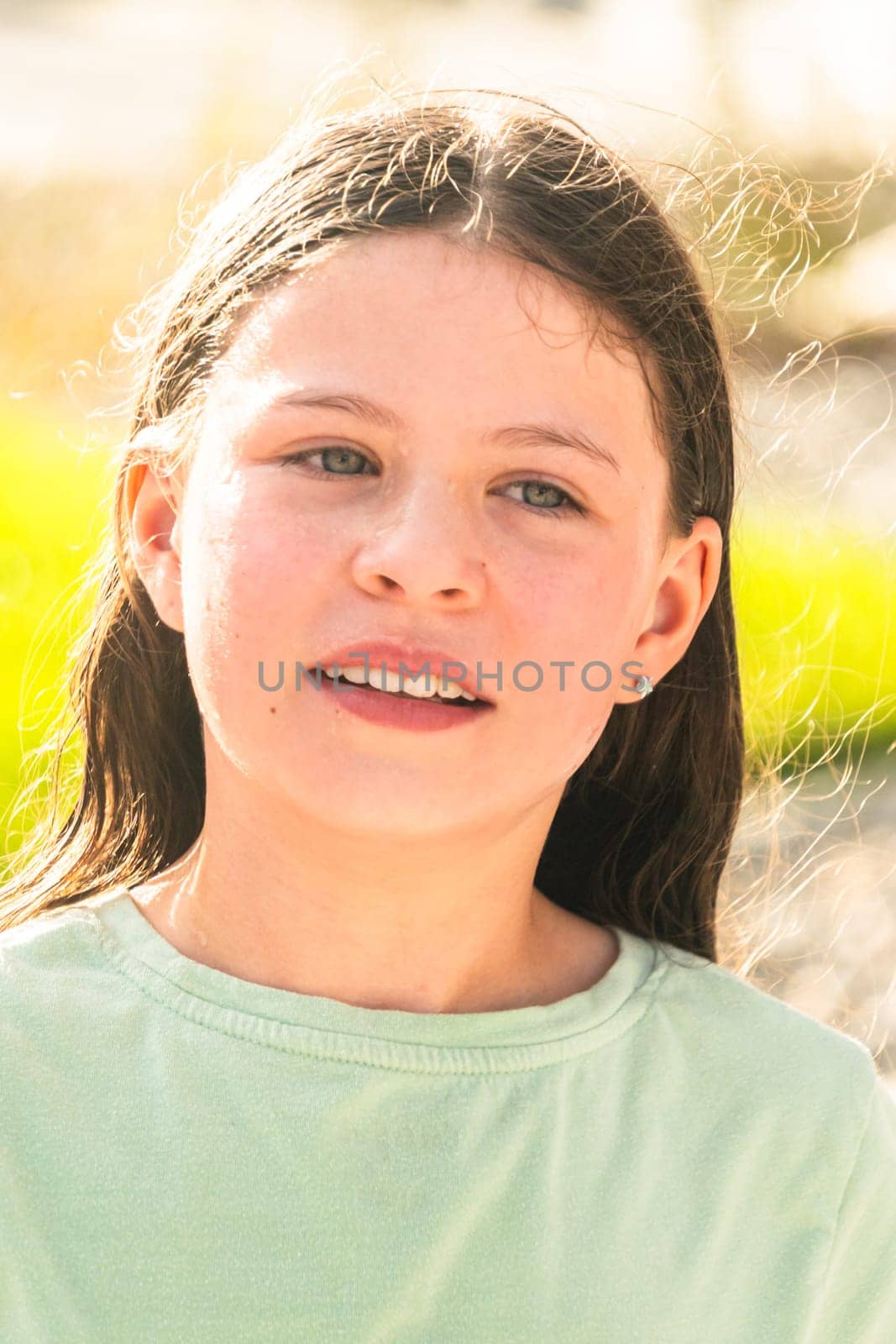 A joyful young girl gleefully gets soaked in refreshing water mist during a hot summer day.