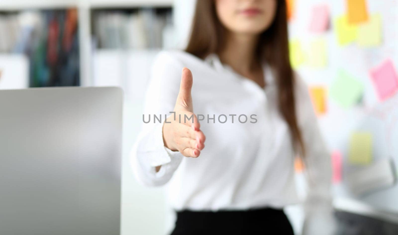 Cheerful female clerk welcoming business partner by shaking hand as sign of future achievements and prospects closeup