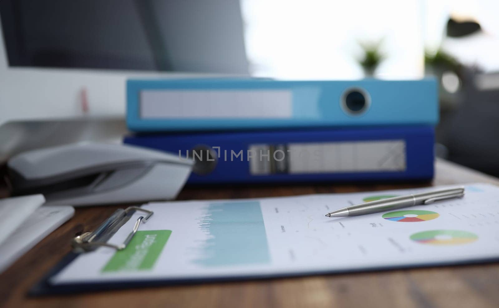 Focus on pen lying on colorful charts and graphs with significant corporation information about business company on wooden desk. Accounting office concept