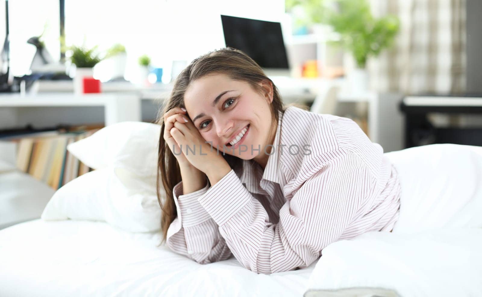 Portrait of wonderful female person looking at camera with happiness and smile. Beautiful lady enjoying relax time in bedstead. Relaxation and vacation concept