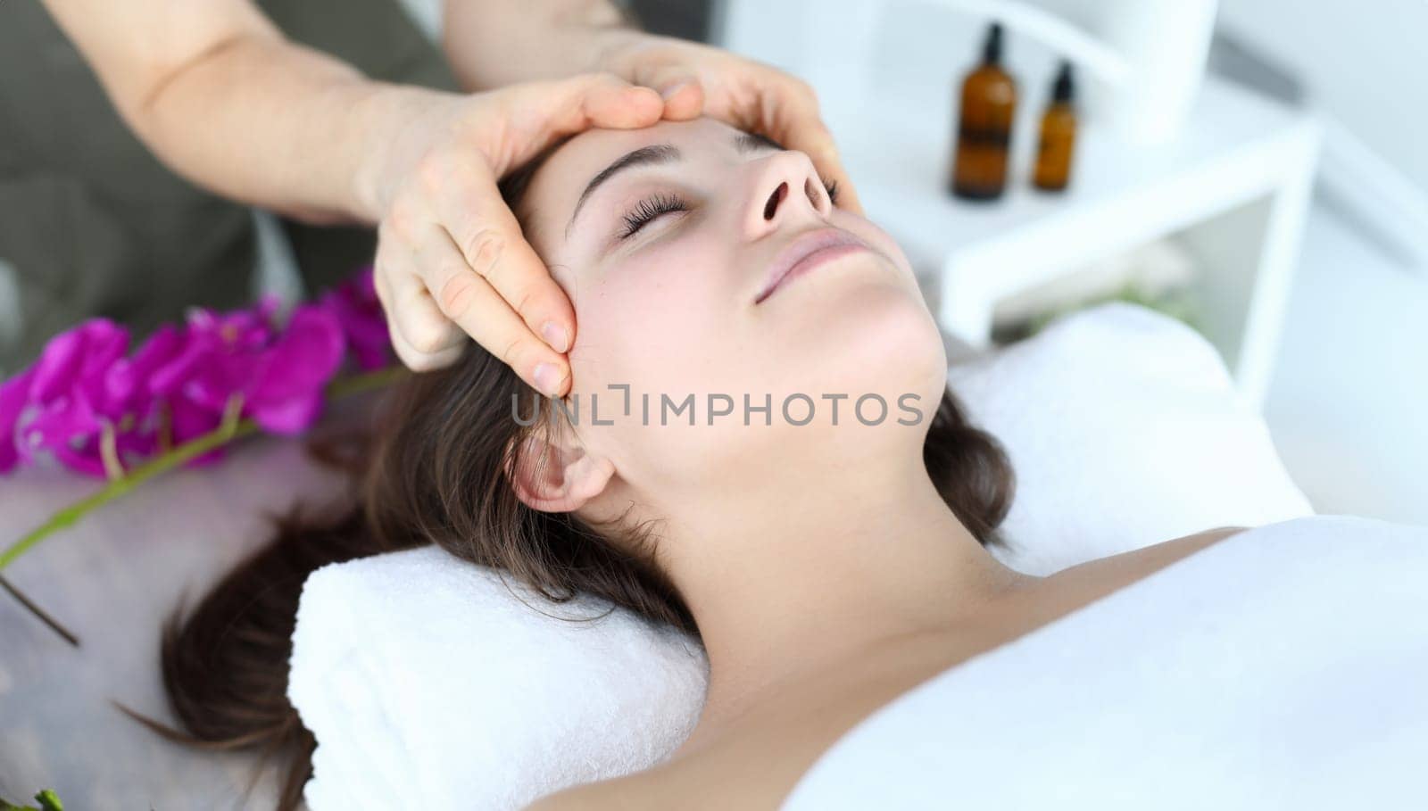 Close-up of beautiful woman enjoying massage on spa treatments in salon. Wonderful female person lying in towel at masseur. Beauty and relaxation concept