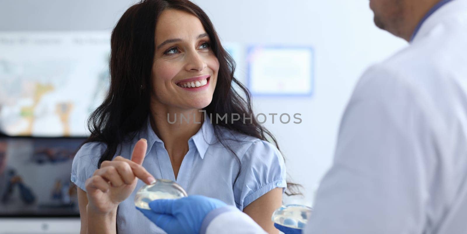 Close-up of cheerful lady looking at doctor with smile. Beautiful female at consultation with plastic surgeon. Silicone implant surgery and anaplasty concept