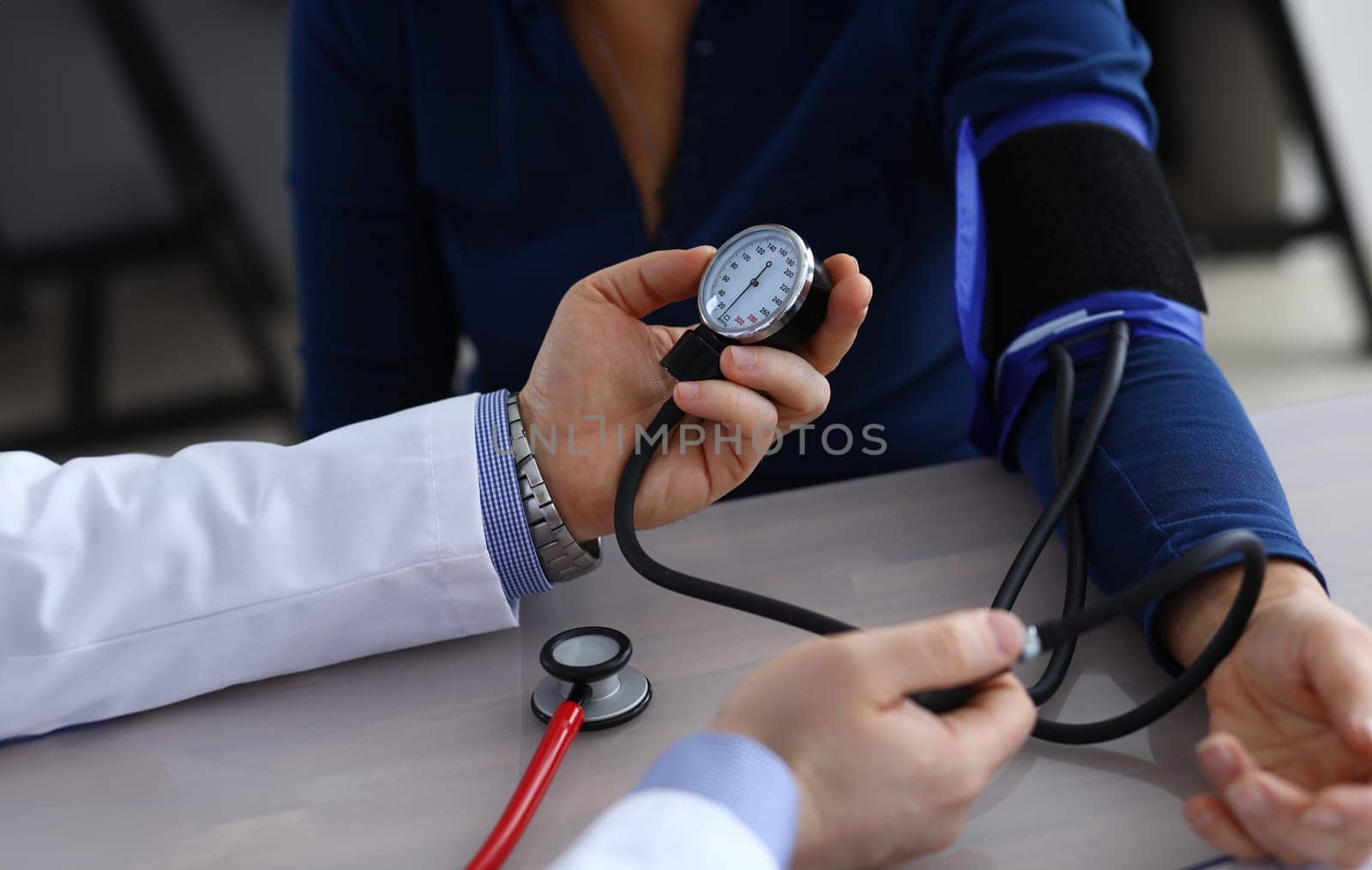 Close-up of doctor hands holding tonometer and measuring pressure to ill patient. Therapist making examination of elderly woman in clinic office. Health care and medicine concept