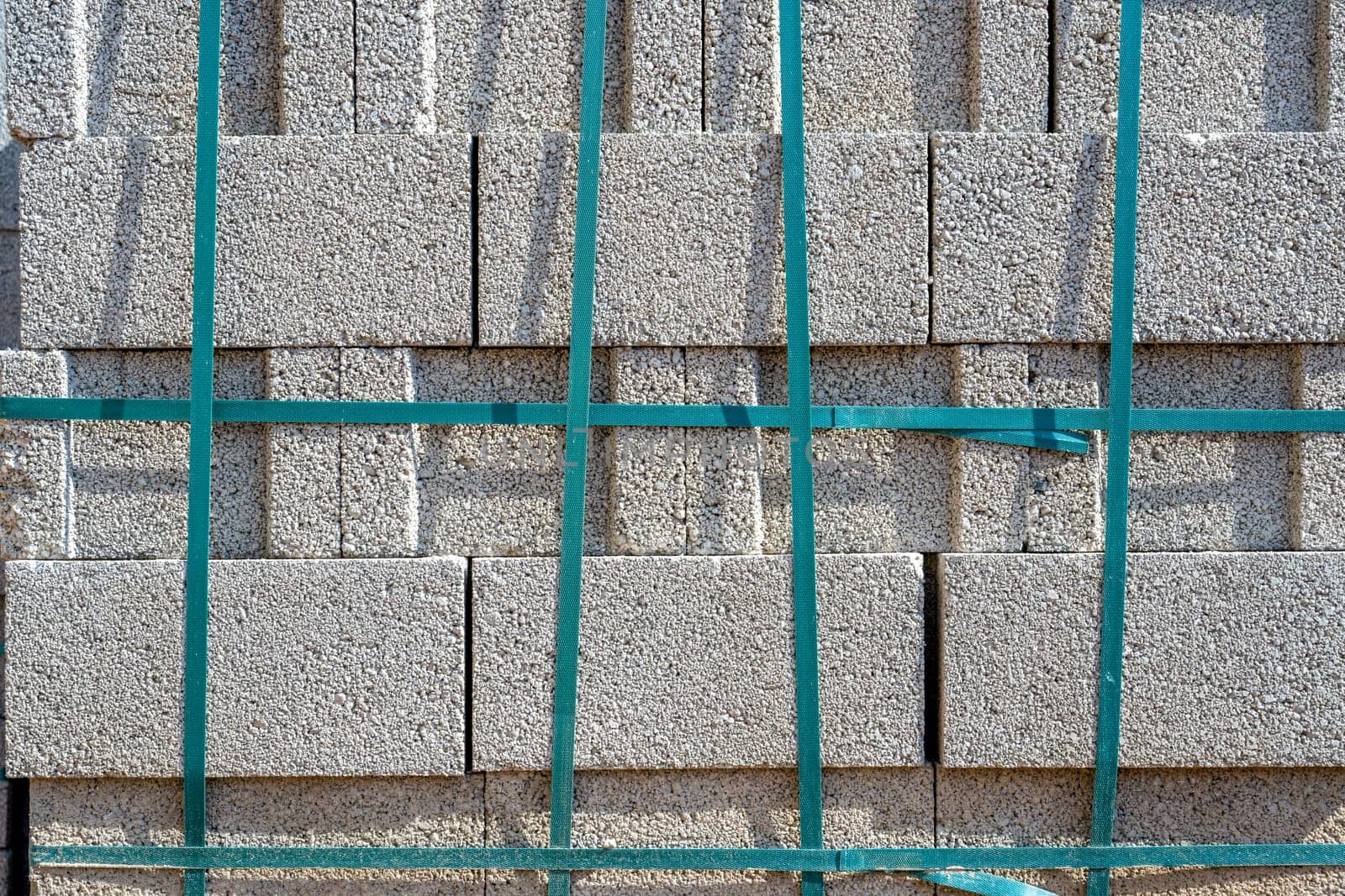 Gray cement cinder block standing on top of each other and tied with strip at construction site