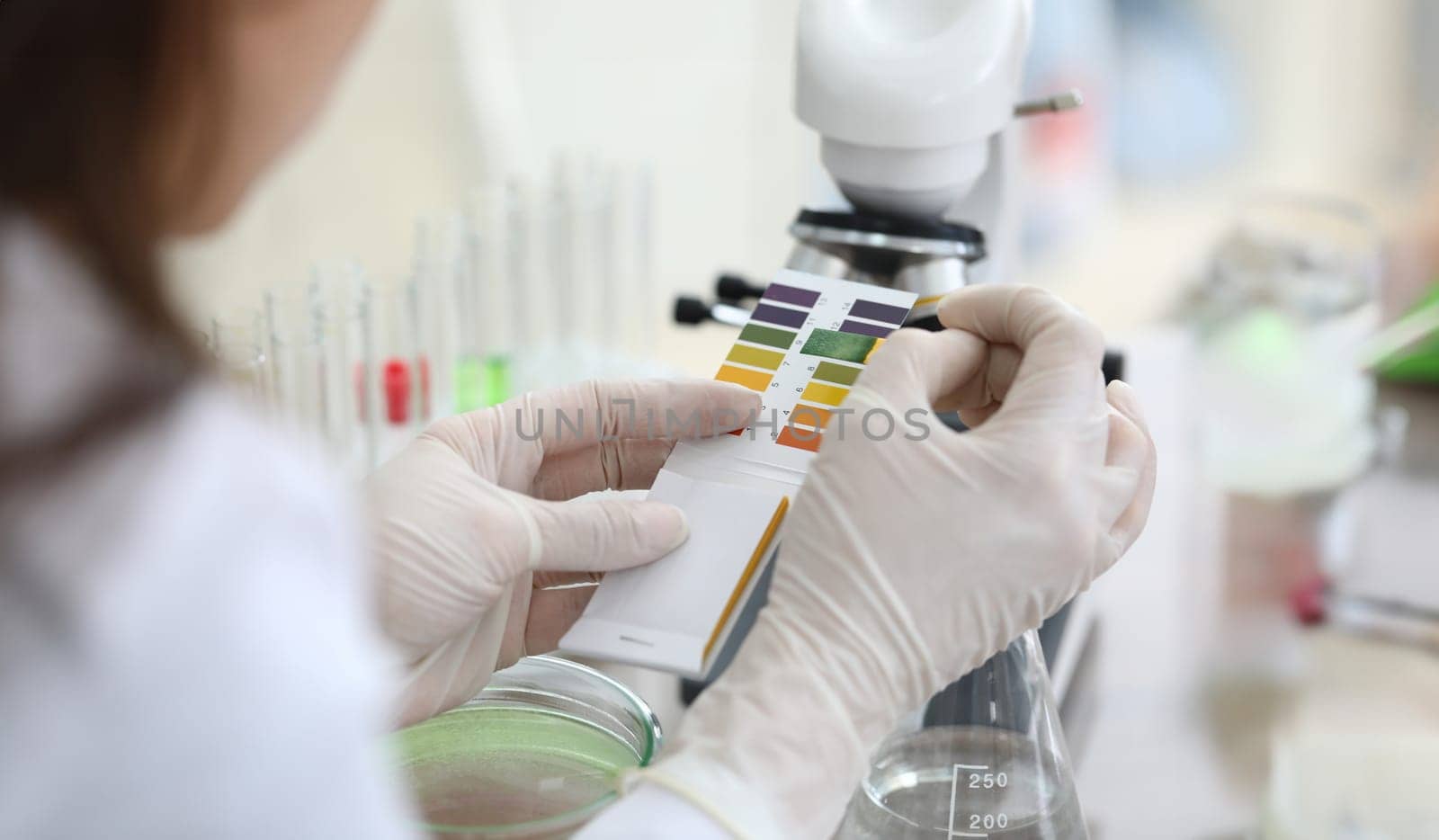 Close-up of scientists hands comparing test colors with samples. Chemist making experiment in laboratory. Chemical experiments and researching concept