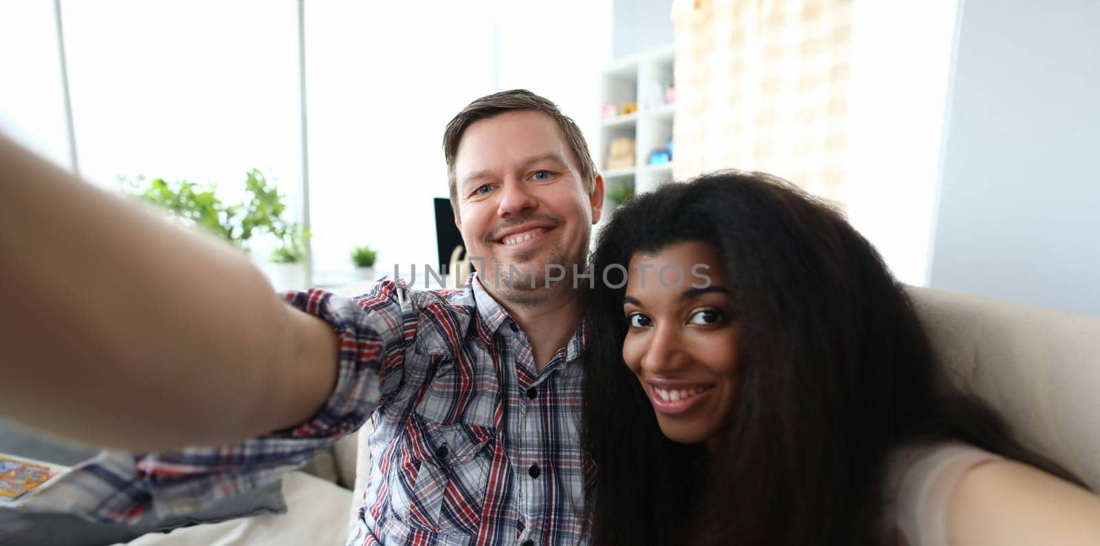 Portrait of sweet couple making selfie on smartphone. Smiling man and afro-american woman. Spouse in good mood. Relationship and leisure fun time together concept