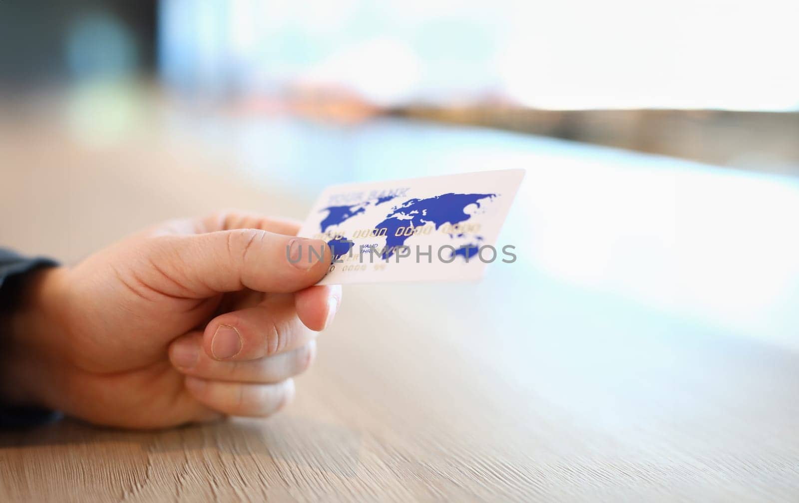 Close-up view of person hand holding white and blue plastic credit card. Online payment via internet or contactless terminal. Modern technology and progress concept