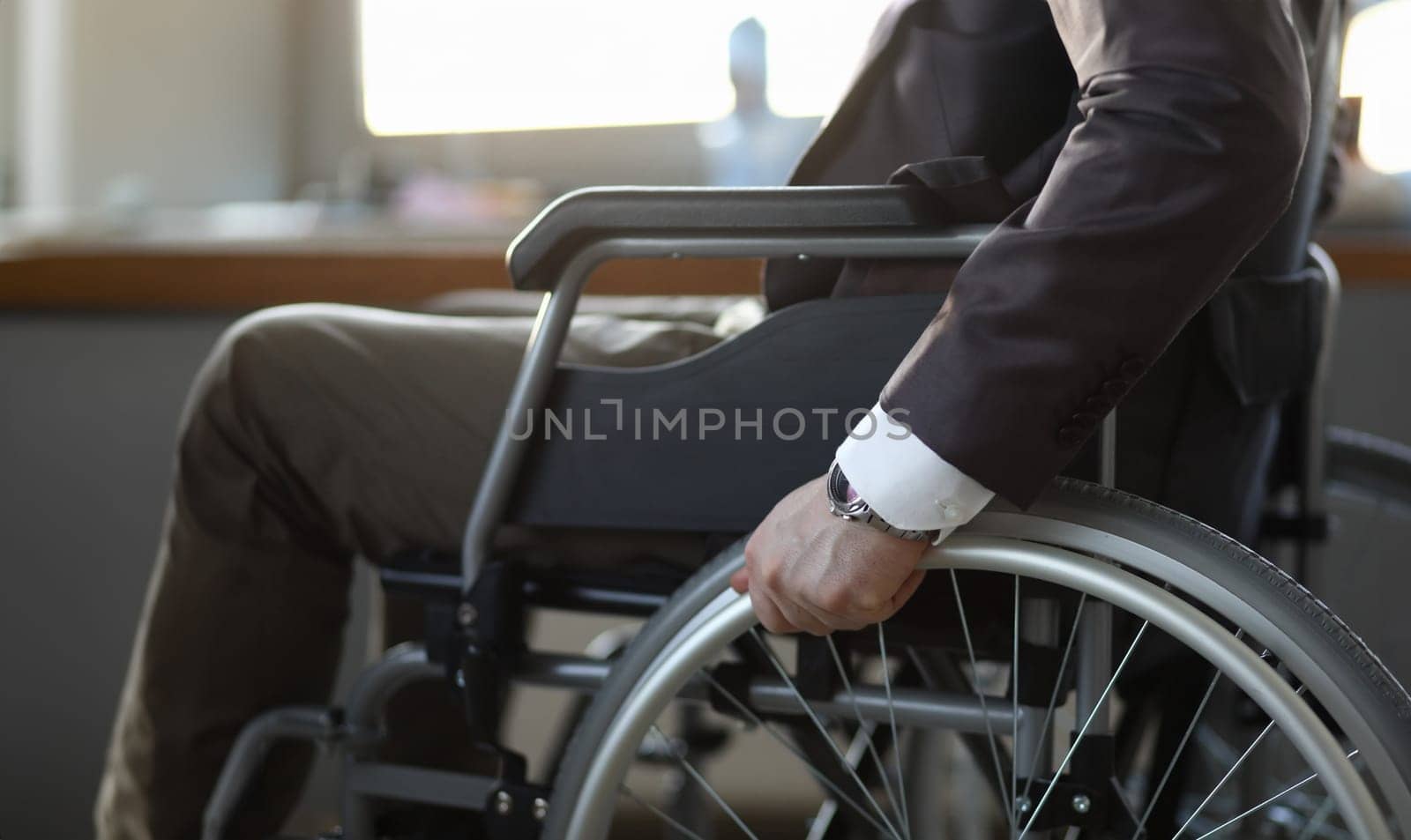 Close-up of disabled man on wheelchair in office wearing presentable suit. Adaptation of people with disabilities in society. Recovery and healthcare concept