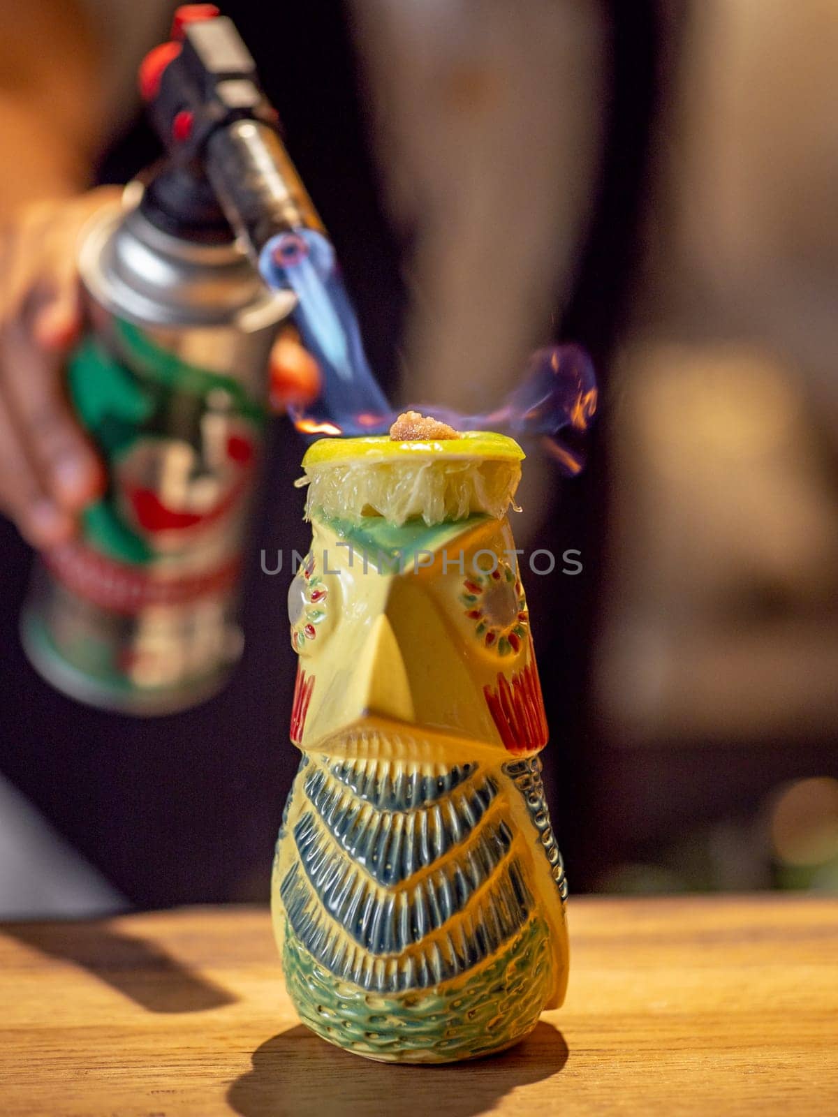 Bartender make tiki drink cocktail with gas torch by fascinadora