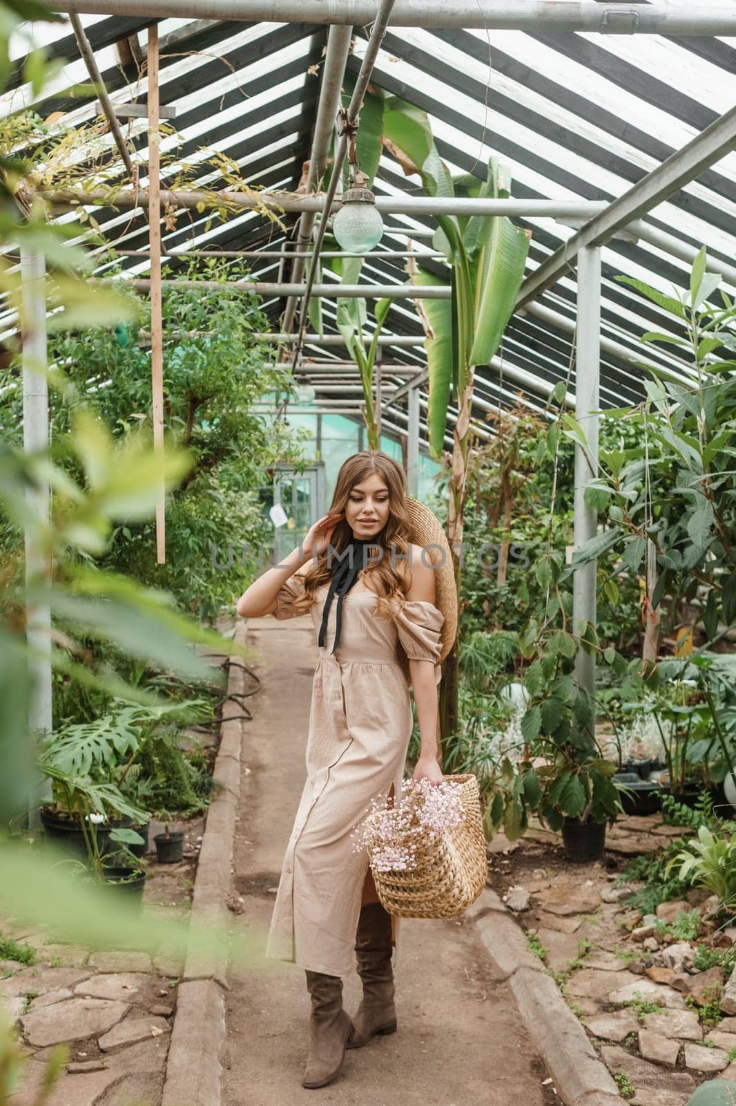 A beautiful young woman takes care of plants in a greenhouse. The concept of gardening and an eco-friendly lifestyle