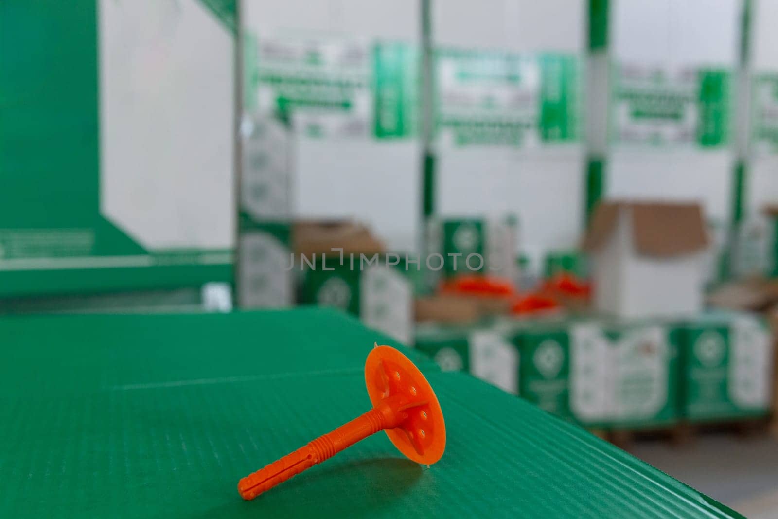 Close up of plastic thermal insulation holder on Box with the same holders in the store warehouse. Dowel Mushroom - the name of the fastener: dowel for thermal insulation, disc dowel, umbrella dowel.